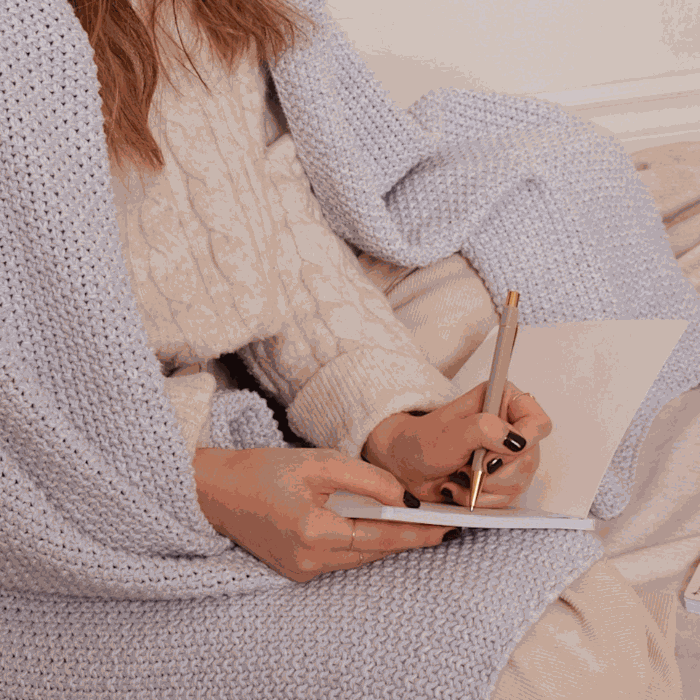 A girl in a cozy environment writing in her Mimi & August floral notebook