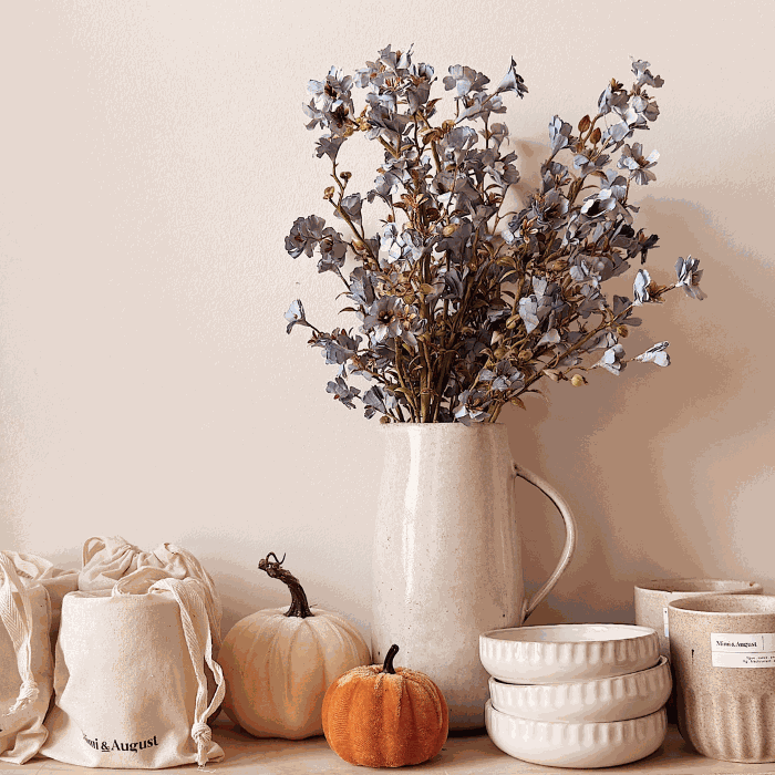 Soy candles vs paraffin comparison featuring beige ceramic soy candles, textured bowls, orange pumpkins, and dried floral arrangement