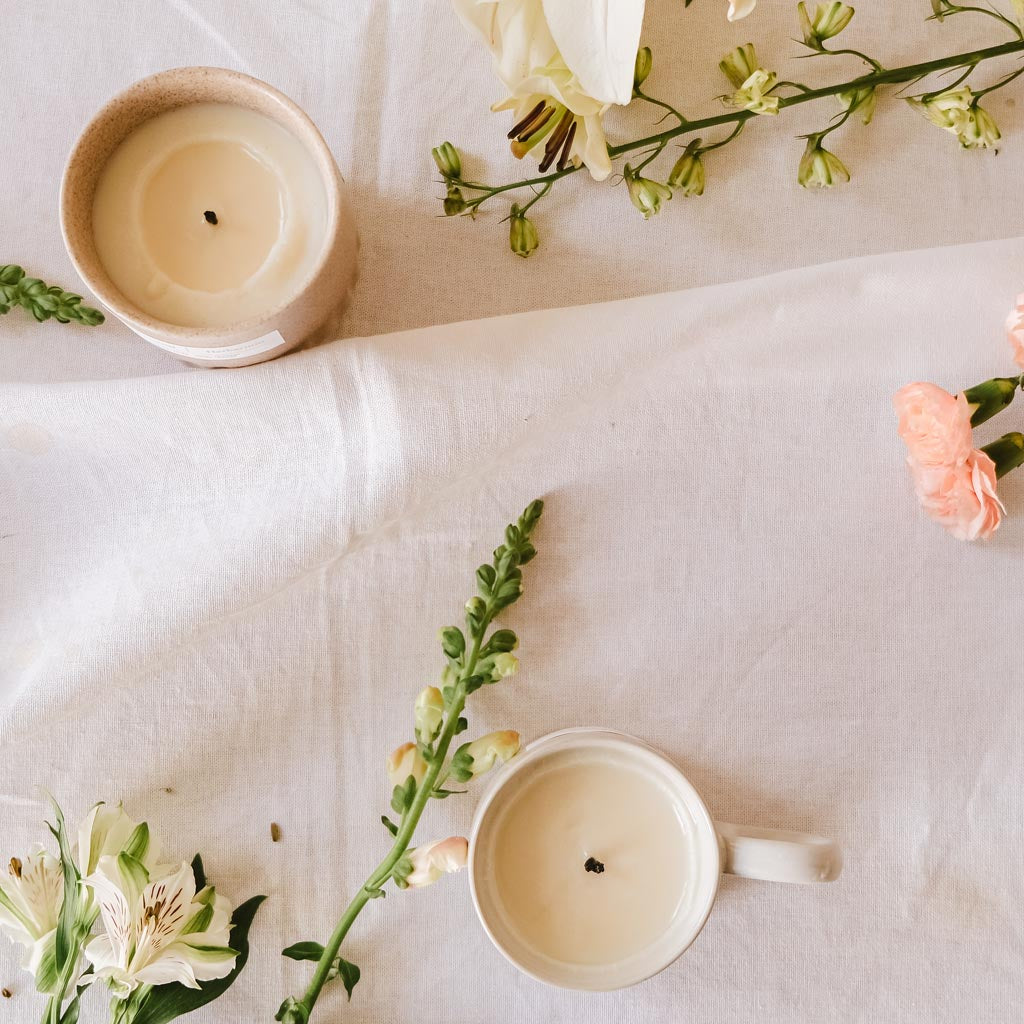 Floral scented candles laid on the ground beside flowers