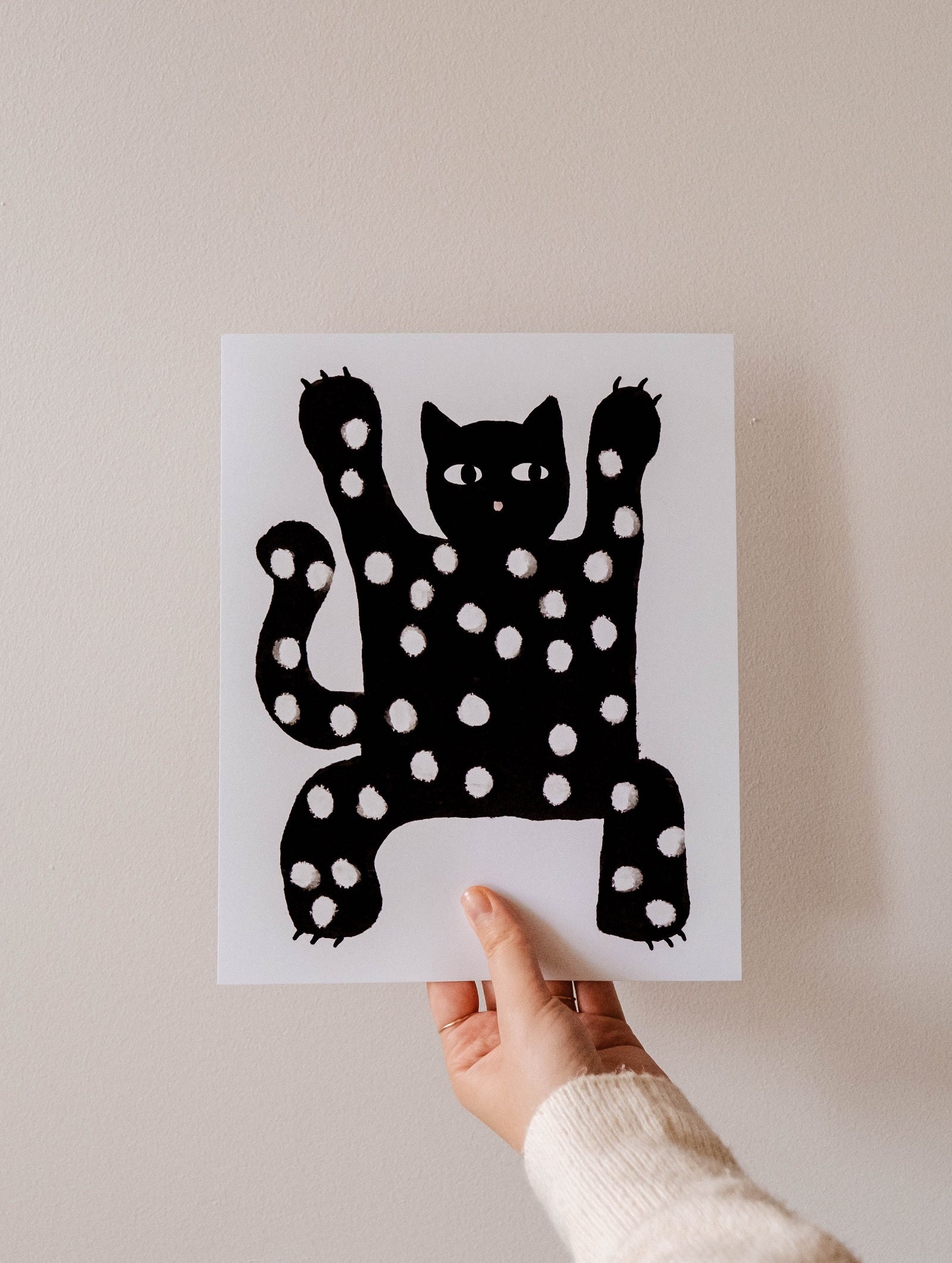 A cat lover holding up a high quality Mimi & August Scary Black Cat Art Print.