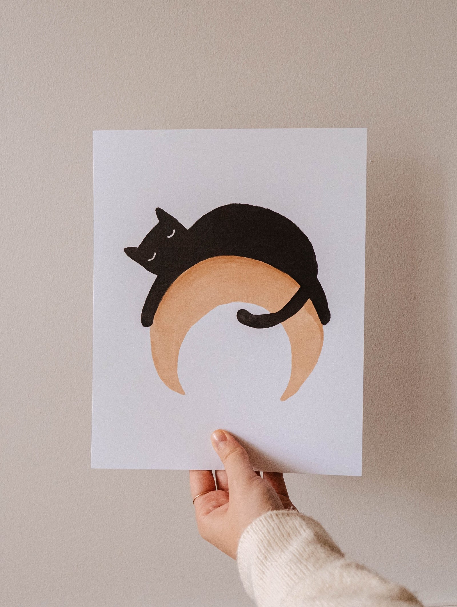 A person holding up a Black Cat on a moon Crescent Art Print by Mimi & August.