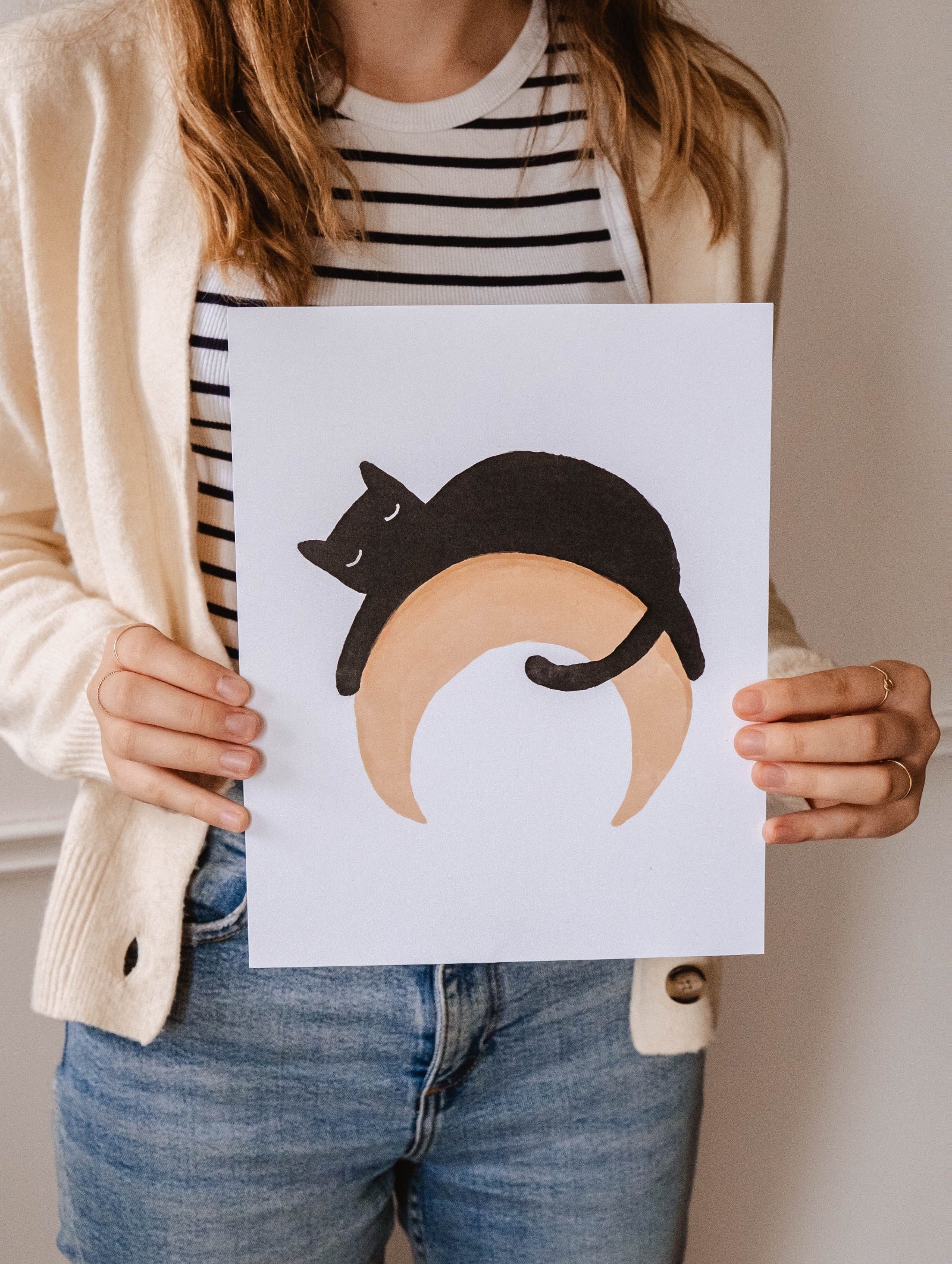 A woman holding up a Black Cat on a crescent moon art print by Mimi & August.
