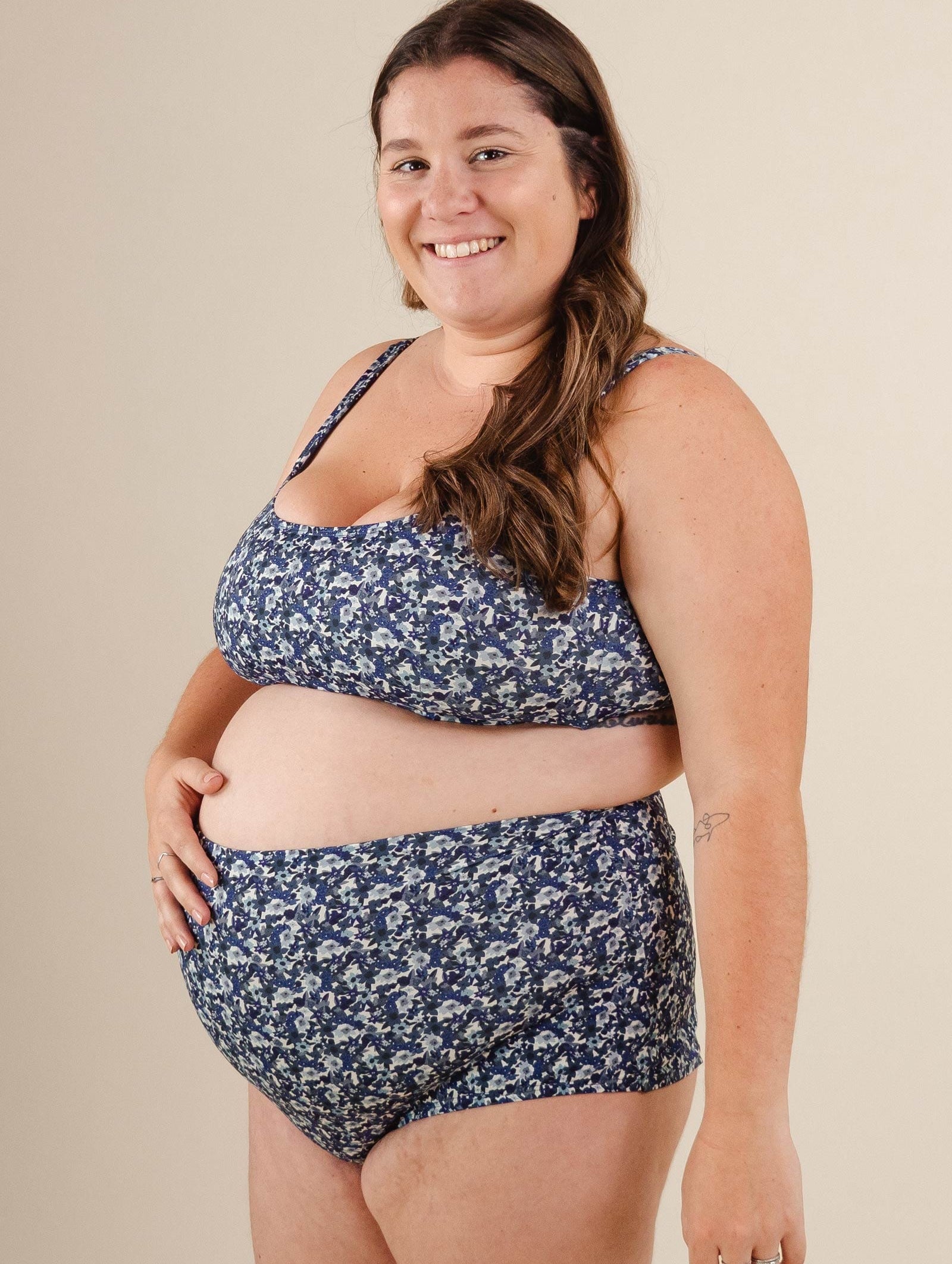 A pregnant woman in a blue floral  Bermudes Moonflower Extra High Waist Bikini Bottom from mimi and august.
