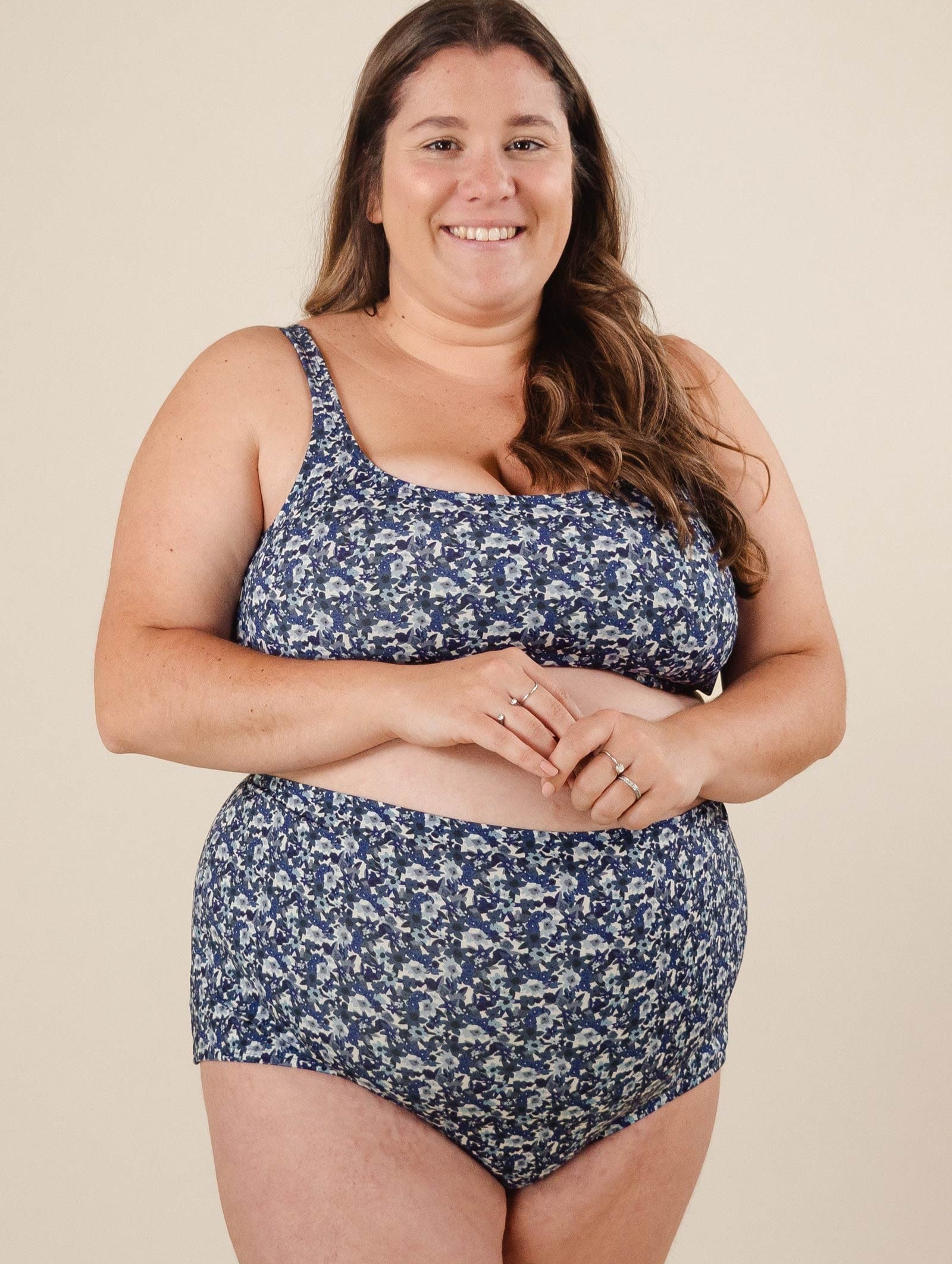 A woman in comfiest bikini bottom in a vibrant blue floral design smiles effortlessly.