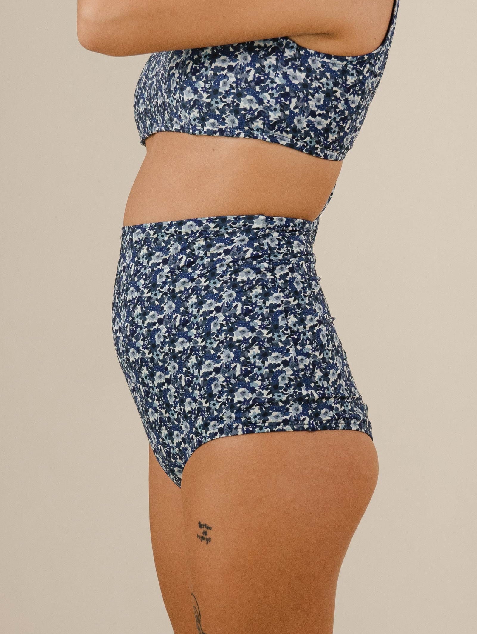 A woman in a blue floral bikini top and Bermudes Moonflower Extra High Waist Bikini Bottom.