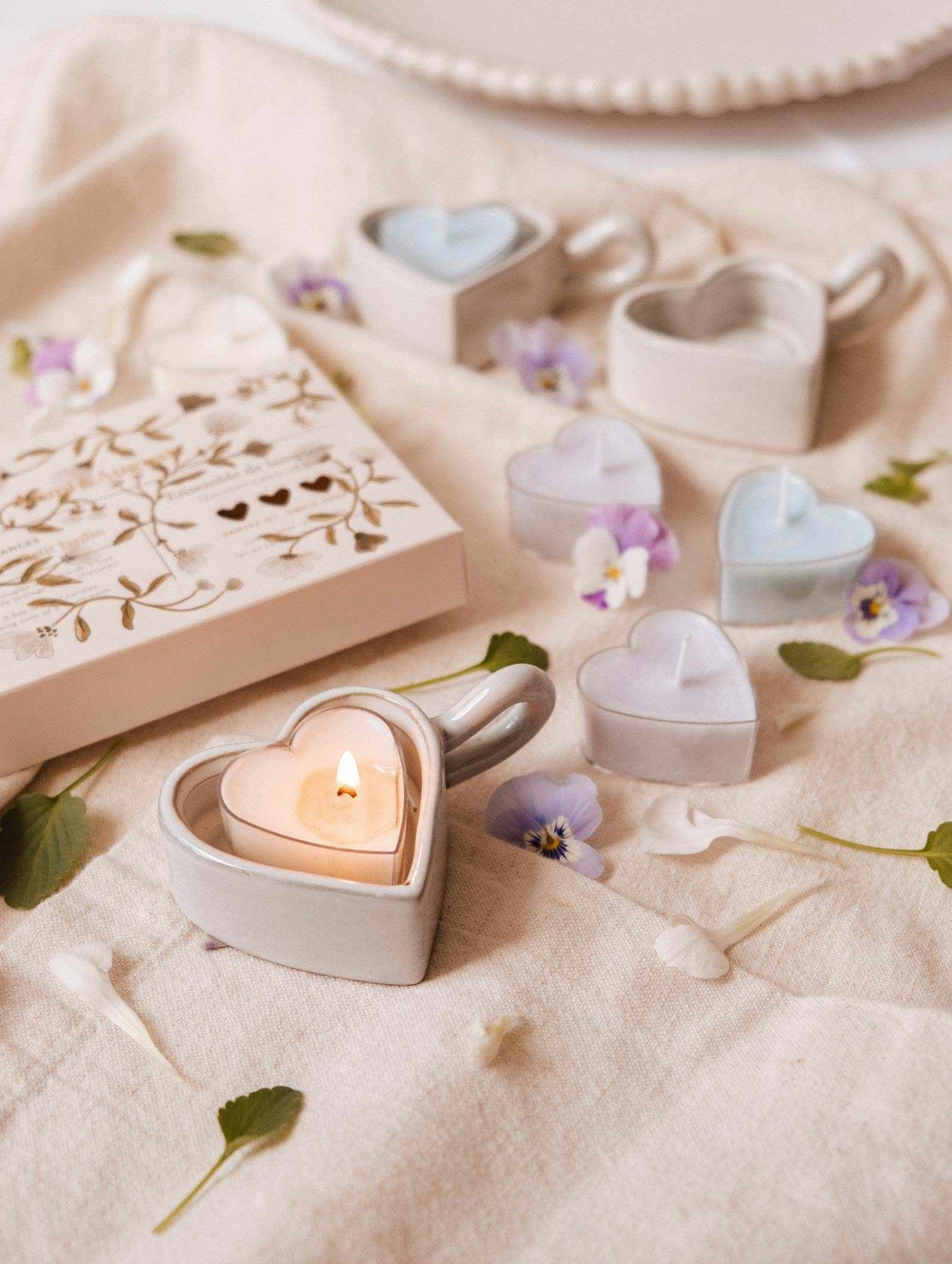 The Blush Hearts Tealight Candle Kit by Mimi & August features heart-shaped soy candles hand-poured in Montreal, displayed in ceramic holders on fabric with scattered flowers and a branded card nearby.