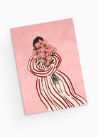 A person in a striped dress holds a bouquet of pink roses on a matching pink background, echoing the elegance and charm of the Bouquet of Roses Greeting Card by Mimi & August. Perfect for sustainable keepsakes, it features floral elegance on recycled paper.