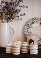 Mimi & August's Ceramic Match Pot holds matches and sits beside cotton-filled ceramic containers, a cream jug with blue flowers, and a floral plate on a wooden surface for a charming display.