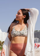 A woman wearing the Chichi Herboria Bralette Bikini Top by mimi and august on the beach.