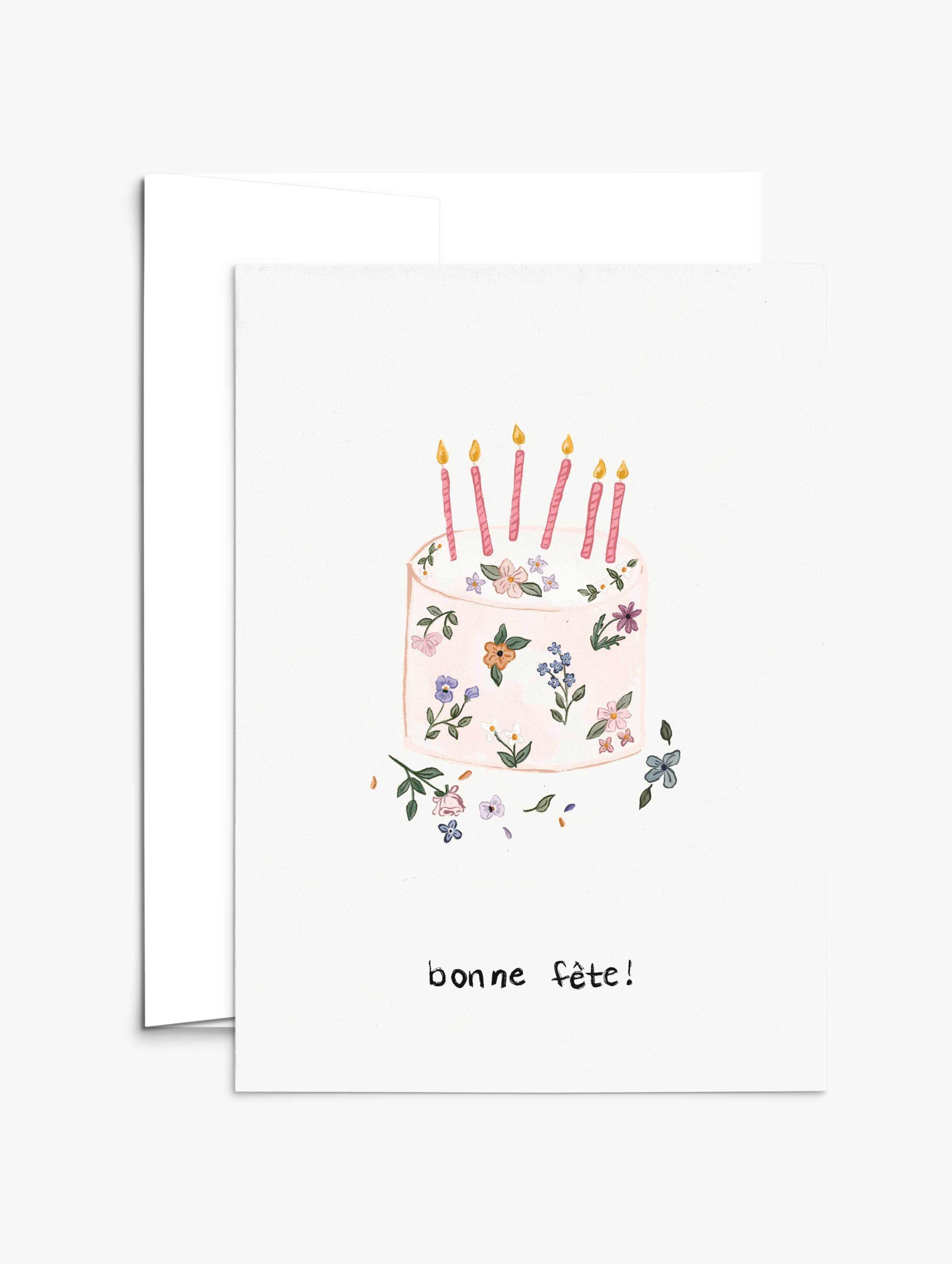 Floral birthday cake with hand-drawn flowers and pink candles on a recycled paper greeting card