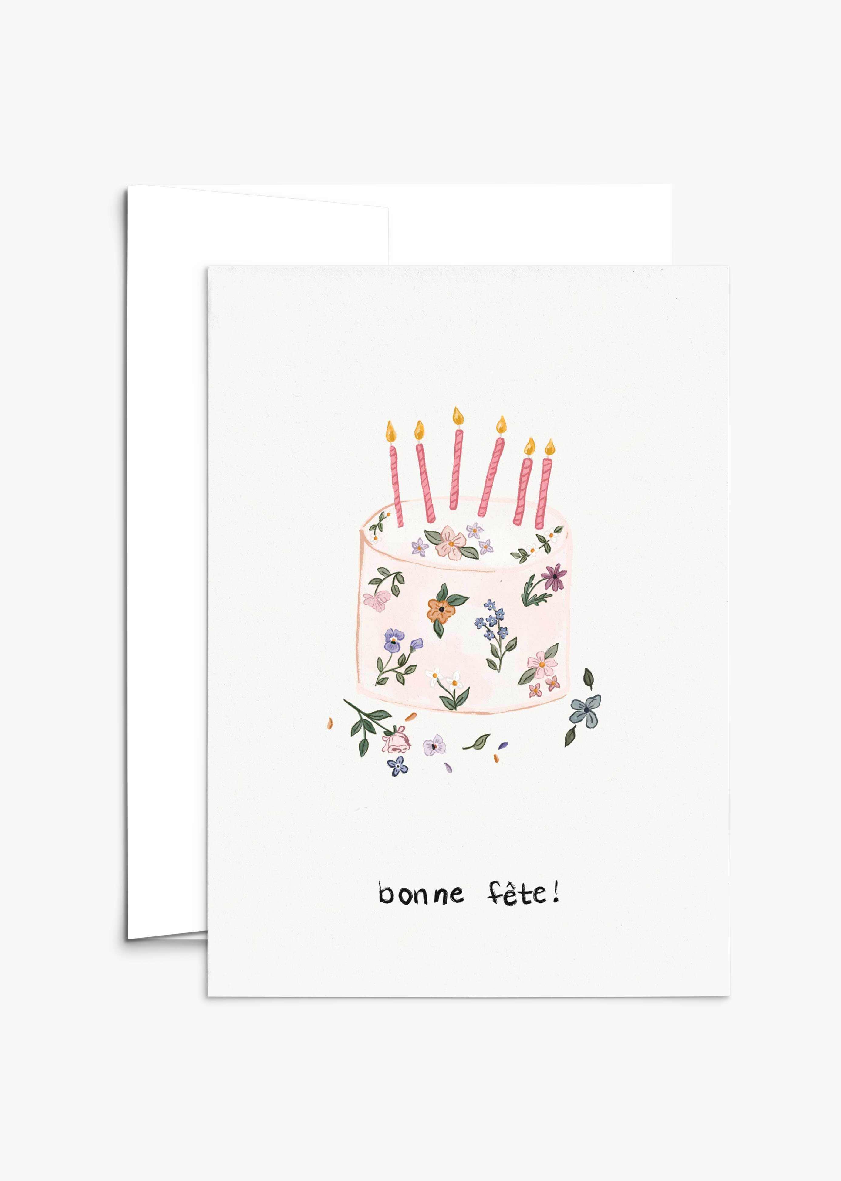Floral birthday cake with hand-drawn flowers and pink candles on a recycled paper greeting card