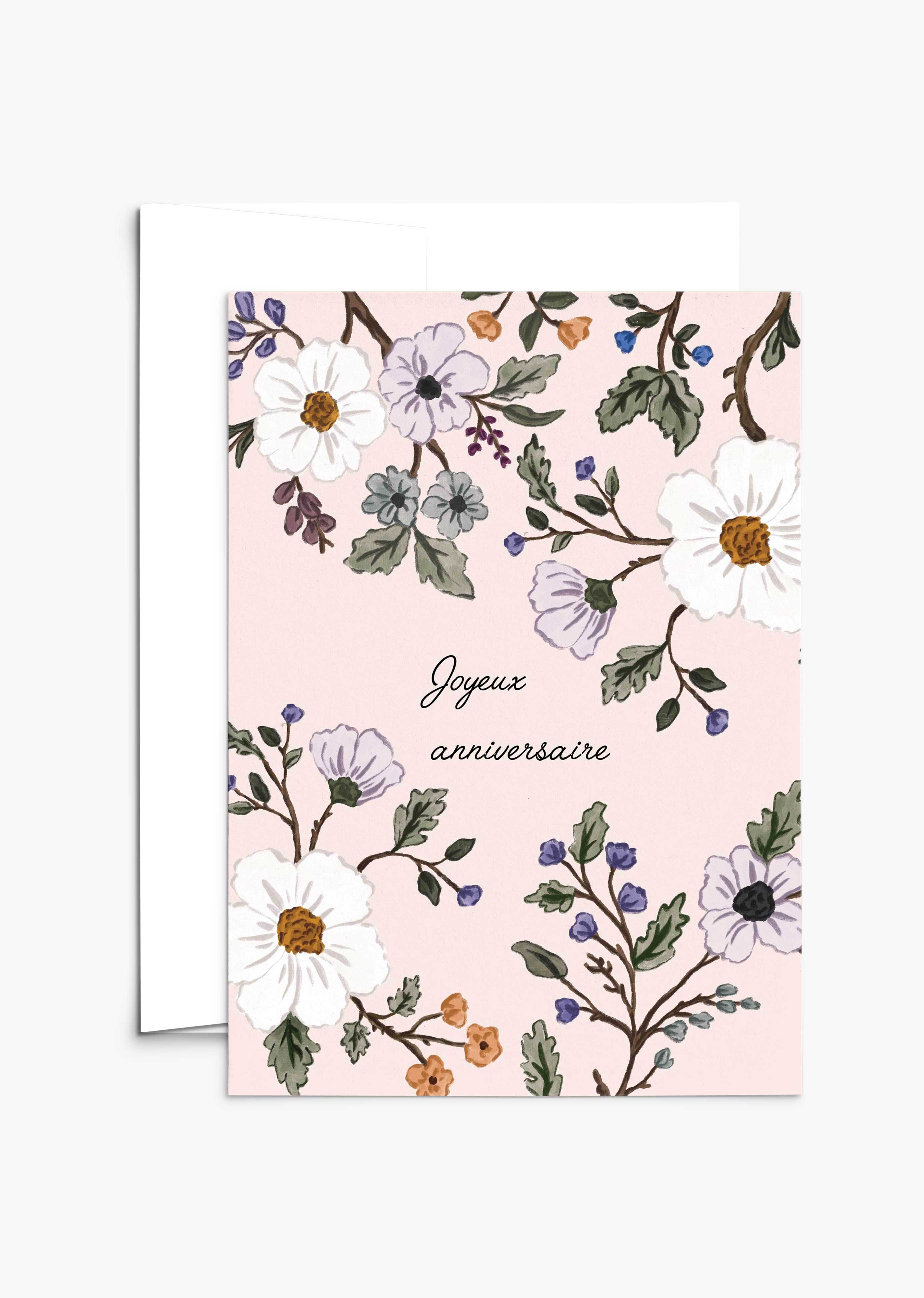 The Botanical Birthday Greeting Card by Mimi & August features "Joyeux anniversaire" on blush pink recycled paper, decorated with white and purple flowers plus green leaves. Includes a partially visible envelope.