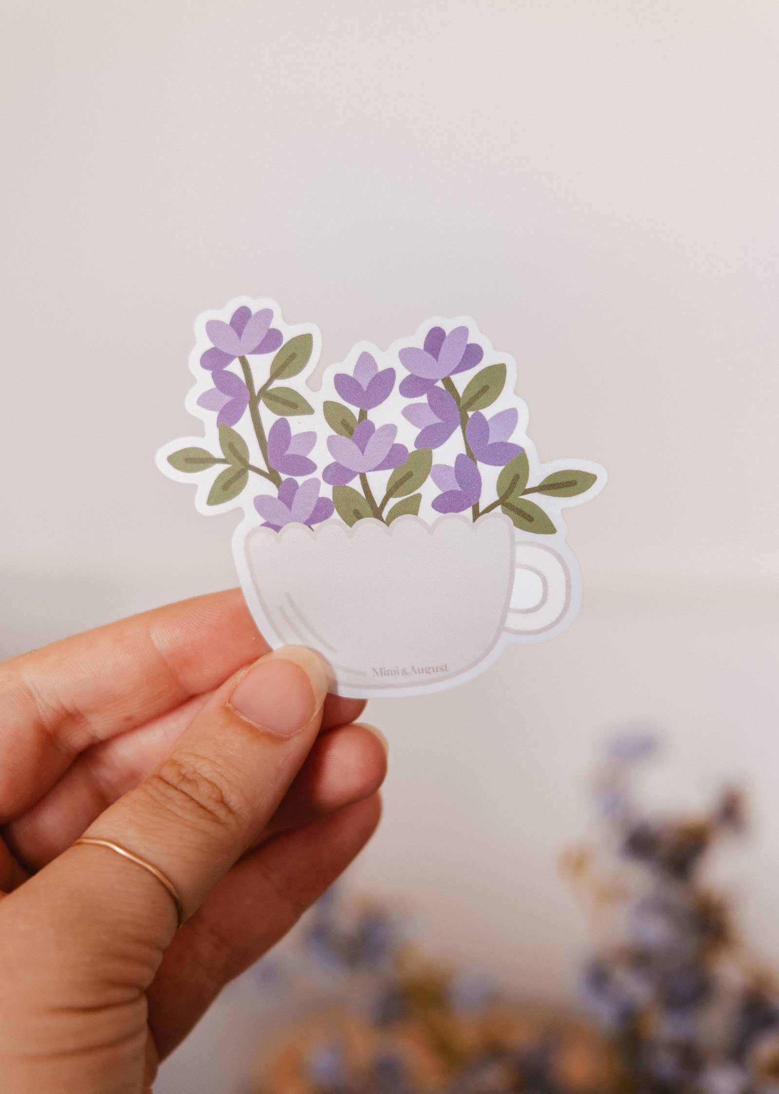 Vinyl sticker of a warm white teacup with purple blooms, durable and water-resistant