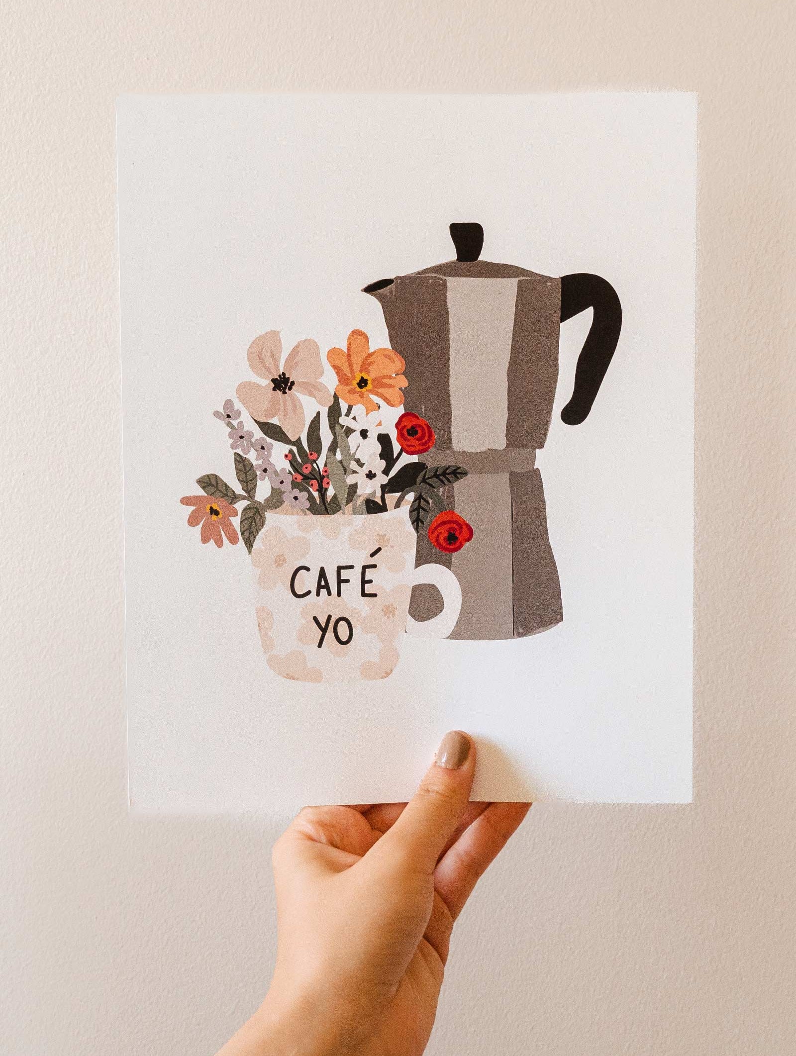 A hand holding up a mimi and august Floral morning coffee pot and flowers.