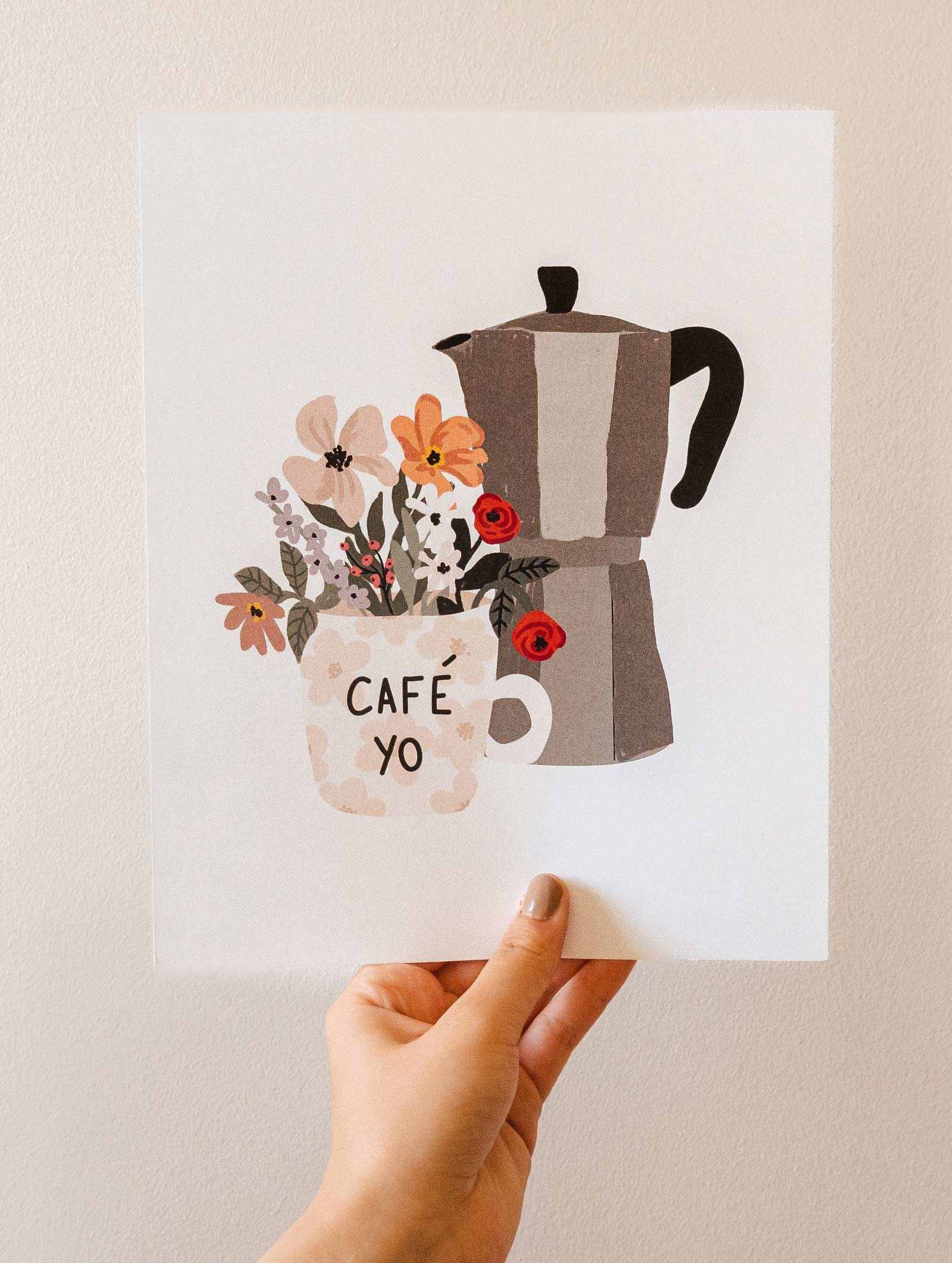 A hand holding up a mimi and august Floral morning coffee pot and flowers.