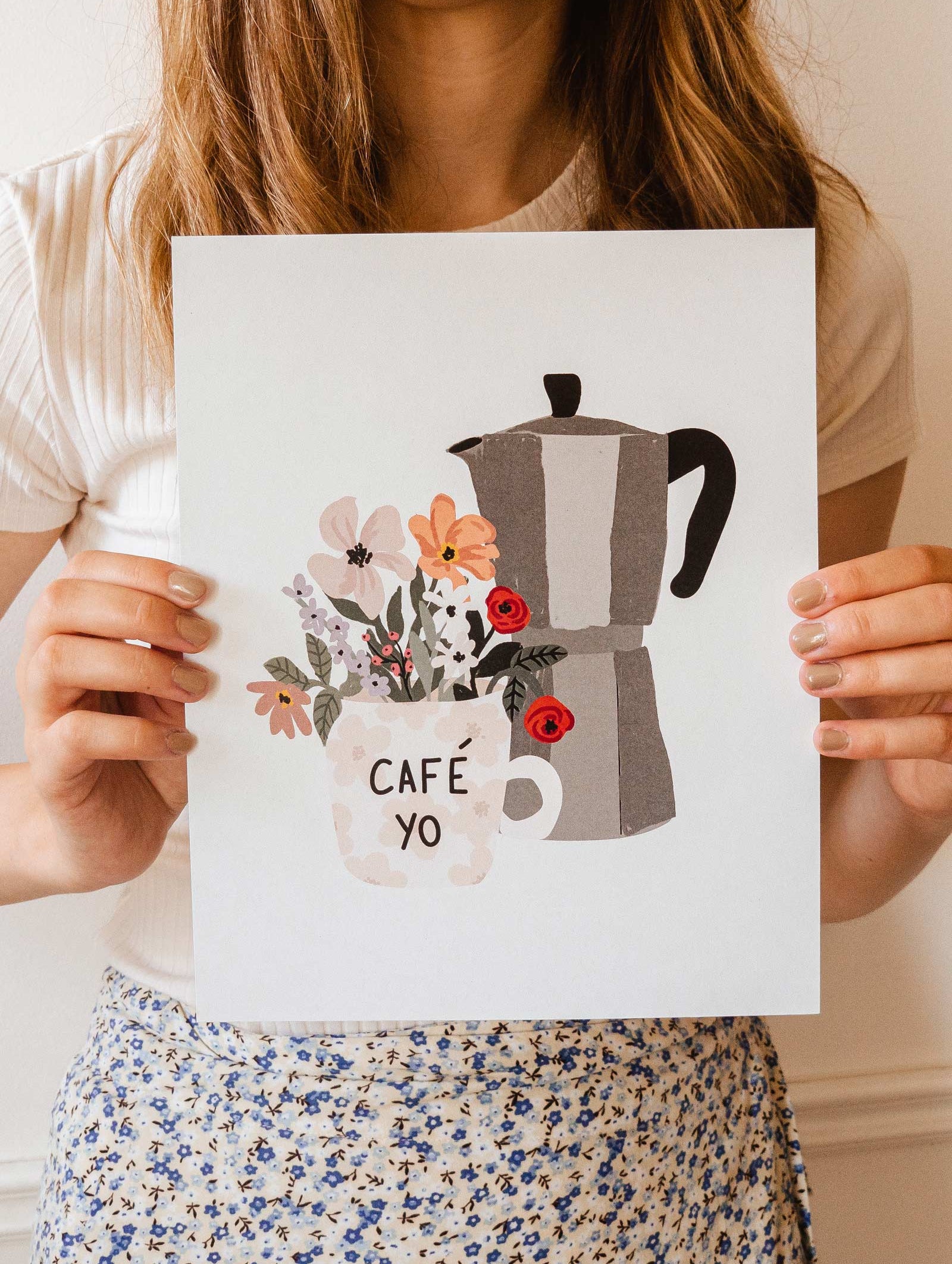 A woman holding up a poster with a Floral morning coffee pot and flowers branded by mimi and august.