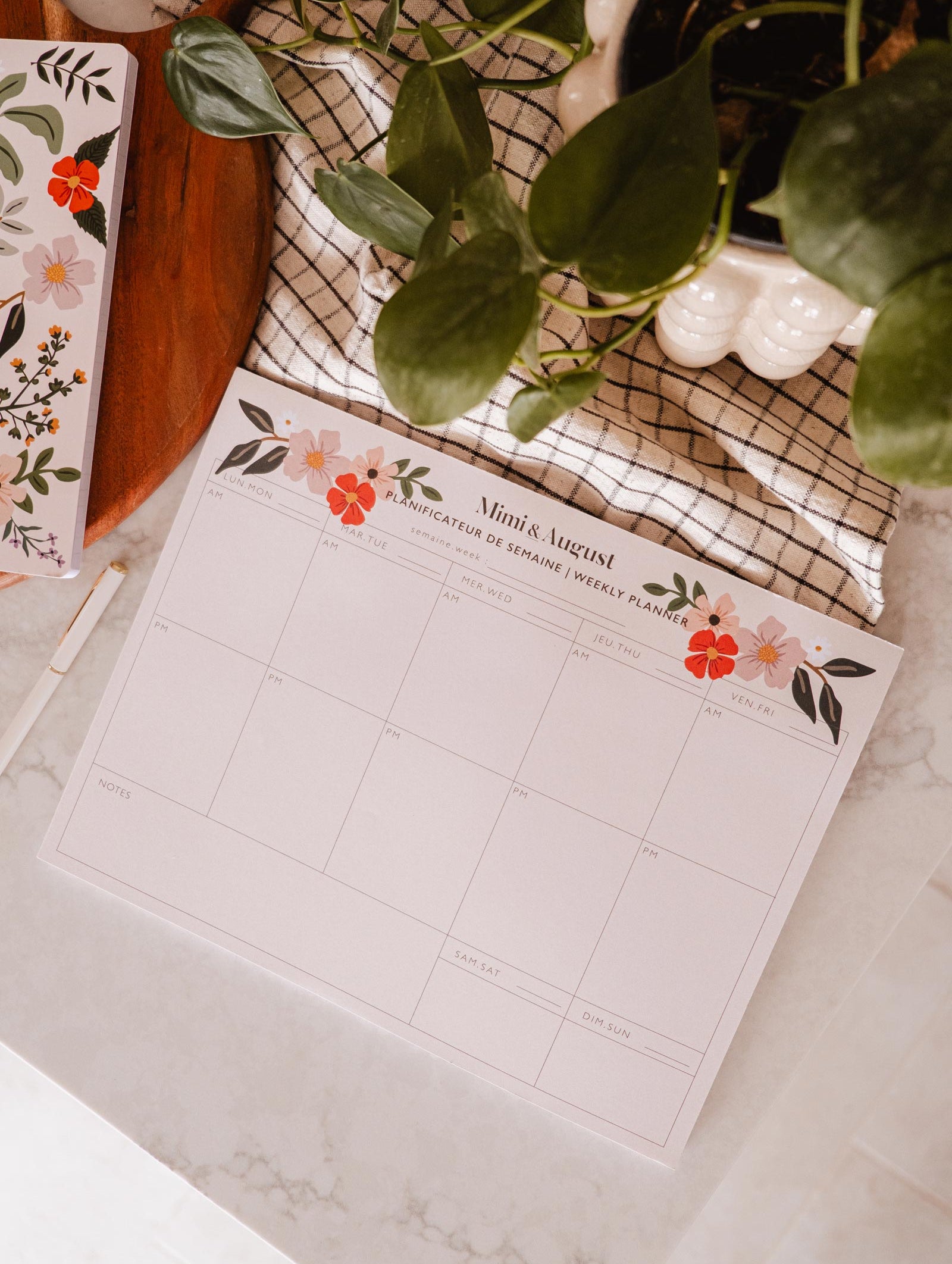 An eco-friendly Flower Bomb - Weekly Planner desk by Mimi & August with a plant next to it.