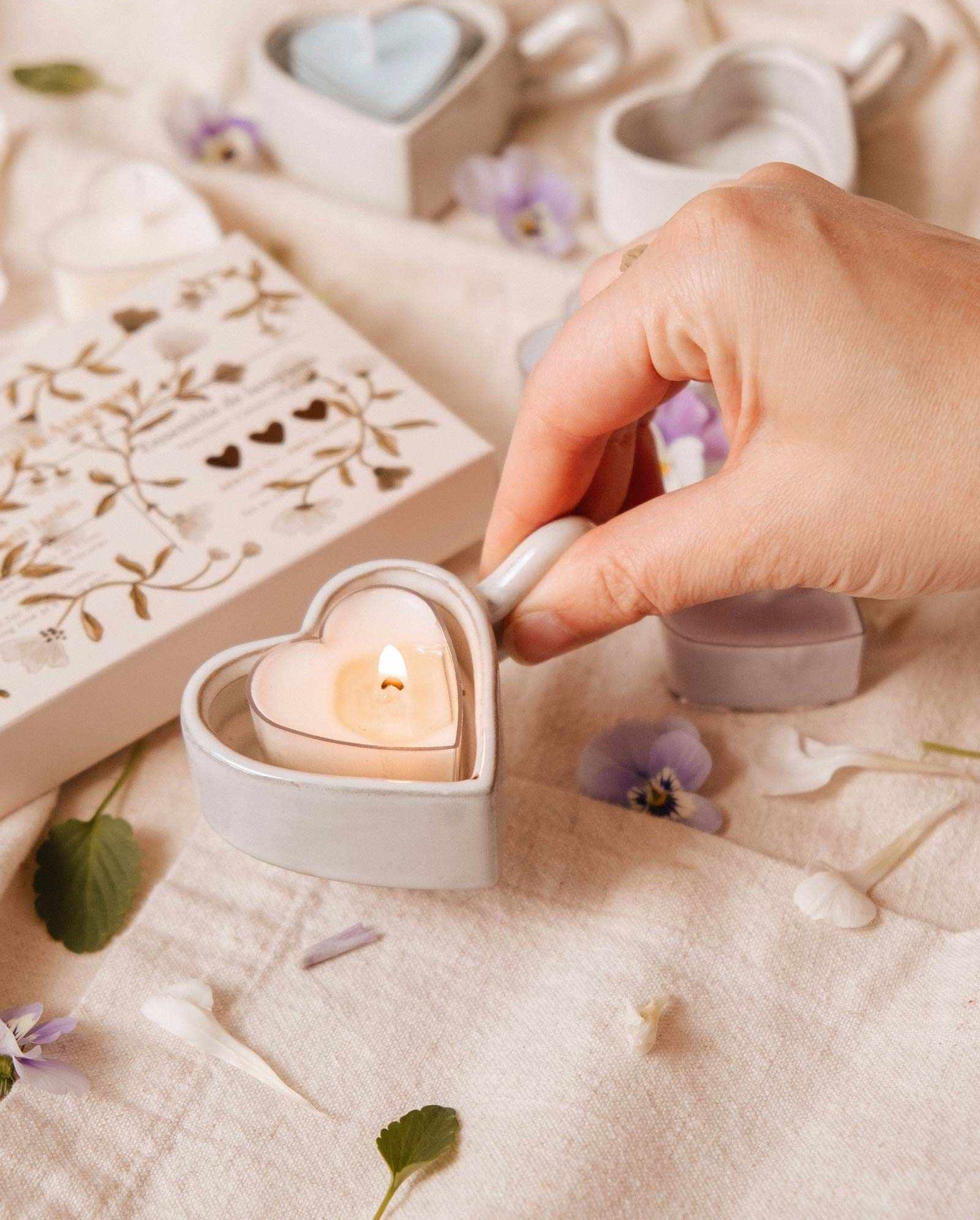 Heart-shaped ceramic tealight holder glowing with pink heart candle inside