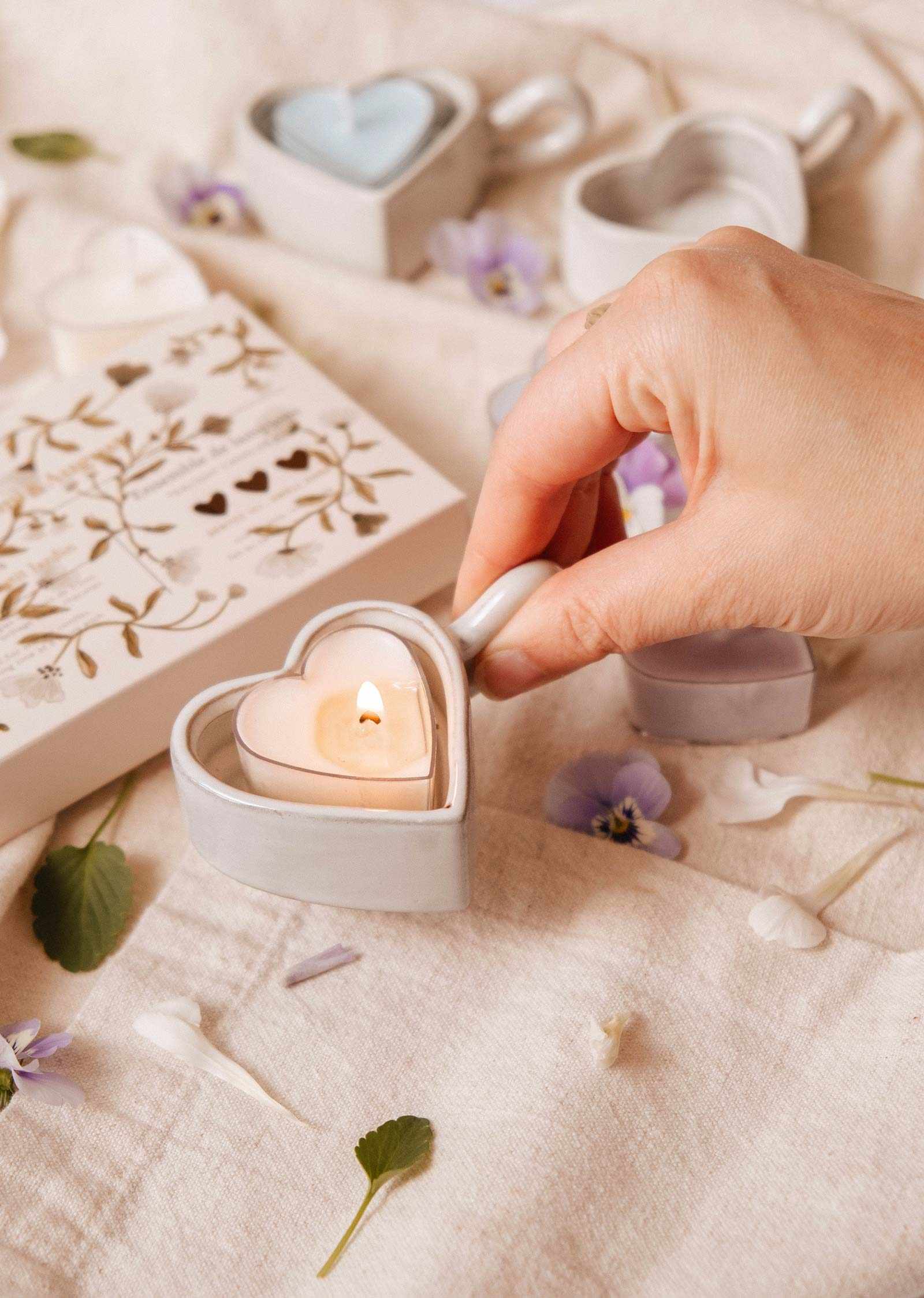 Heart-shaped ceramic tealight holder glowing with pink heart candle inside