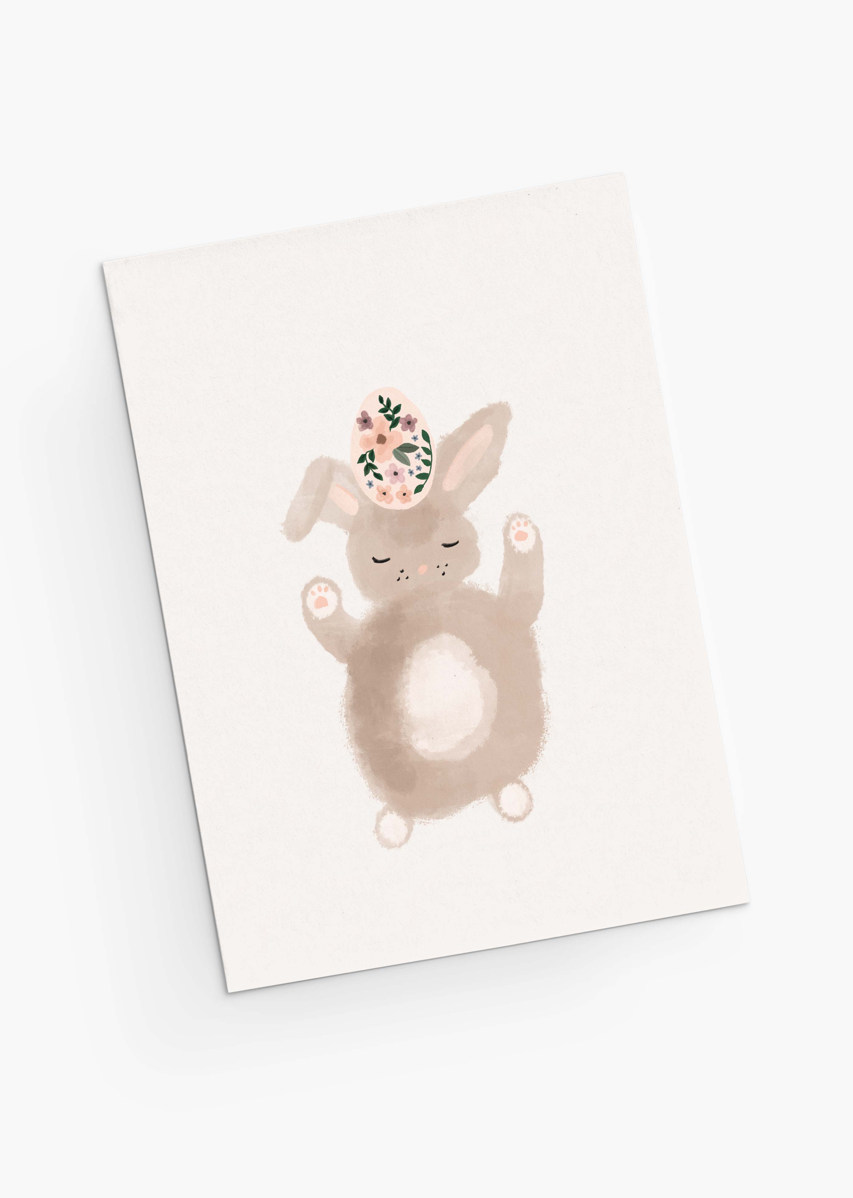 The Lapinot Greeting Card from Mimi & August features a cute bunny with closed eyes balancing a floral-patterned egg on its head. Rendered in delicate watercolor, it perfectly encapsulates springtime whimsy, making it ideal for an Easter card.