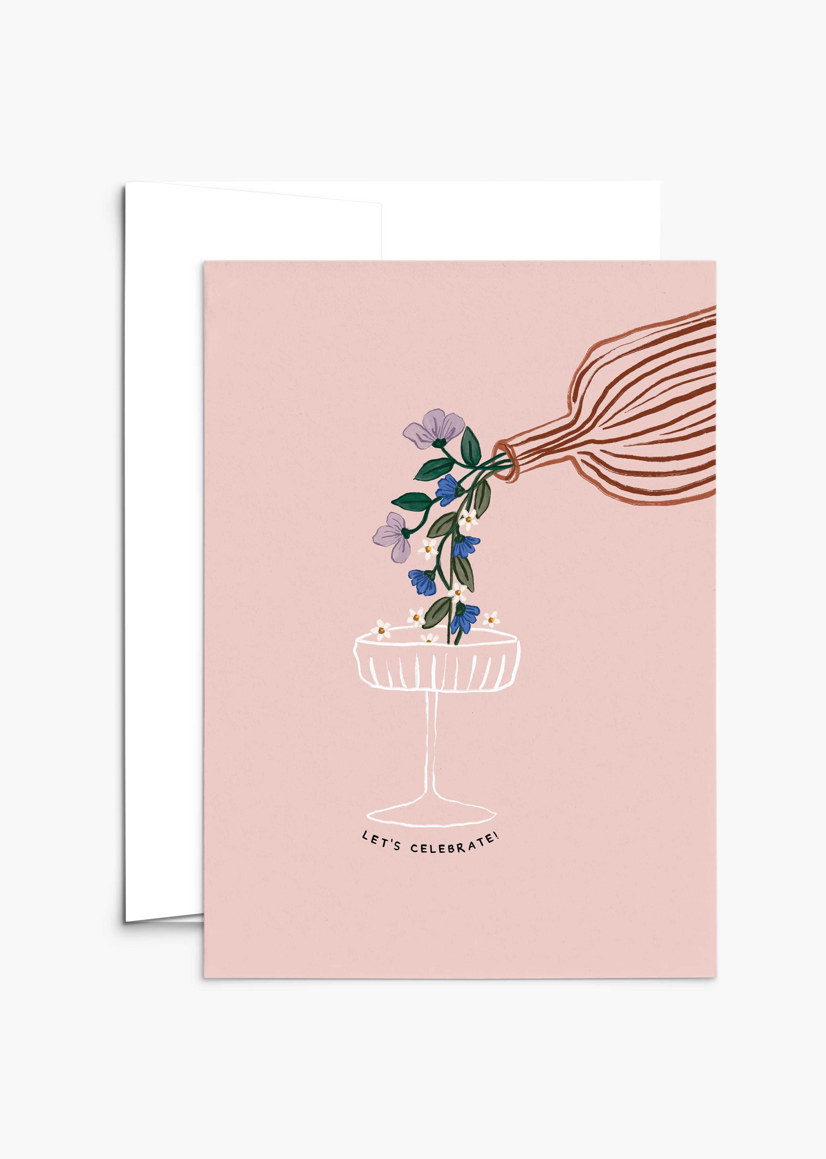 The Let's Celebrate Greeting Card by Mimi & August features a hand pouring flowers into a champagne glass on a pink background with "LET'S CELEBRATE!" below. Printed on recycled paper, it's the perfect card for any celebration.
