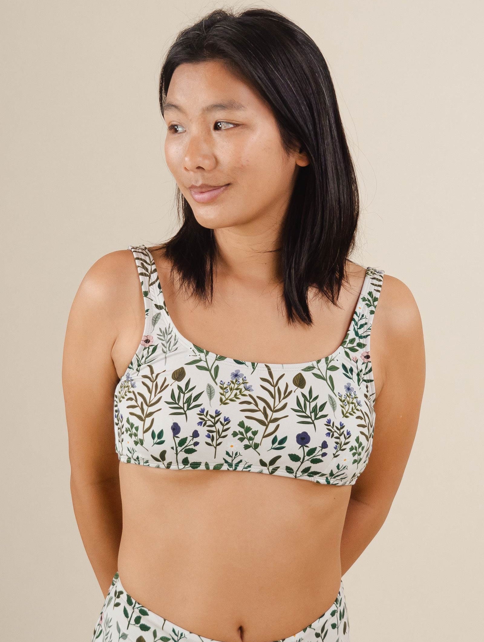 A woman in a Lima Herboria Bralette Bikini Top by mimi and august with a floral print.