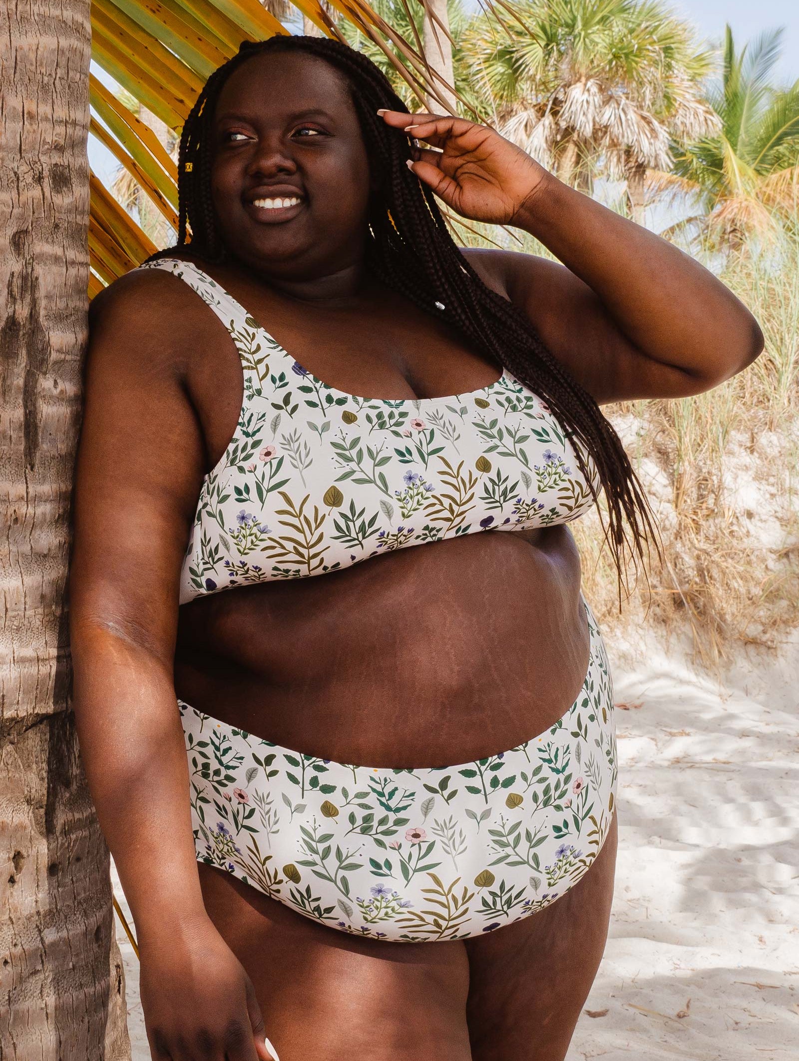 African woman in a mimi and august Lima Herboria Bralette Bikini Top standing next to palms.