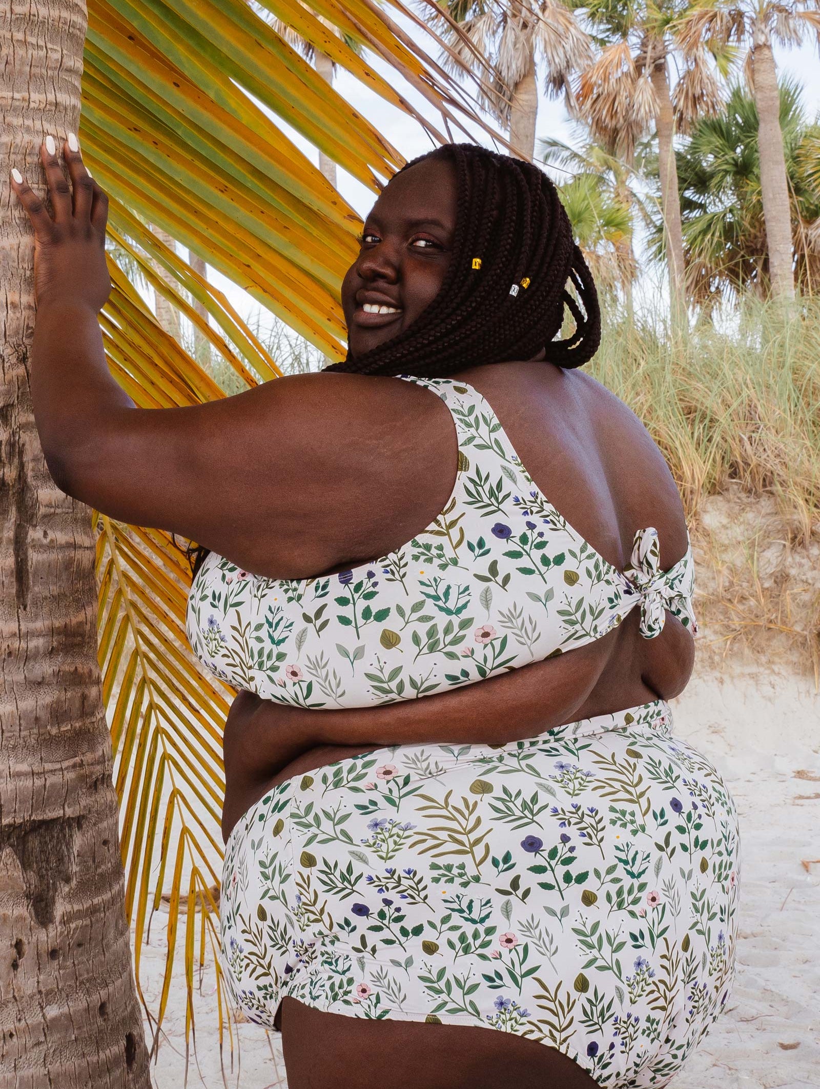 A fashionable woman wearing the Lima Herboria Bralette Bikini Top standing next to a palm tree on Key Biscayne in Miami.