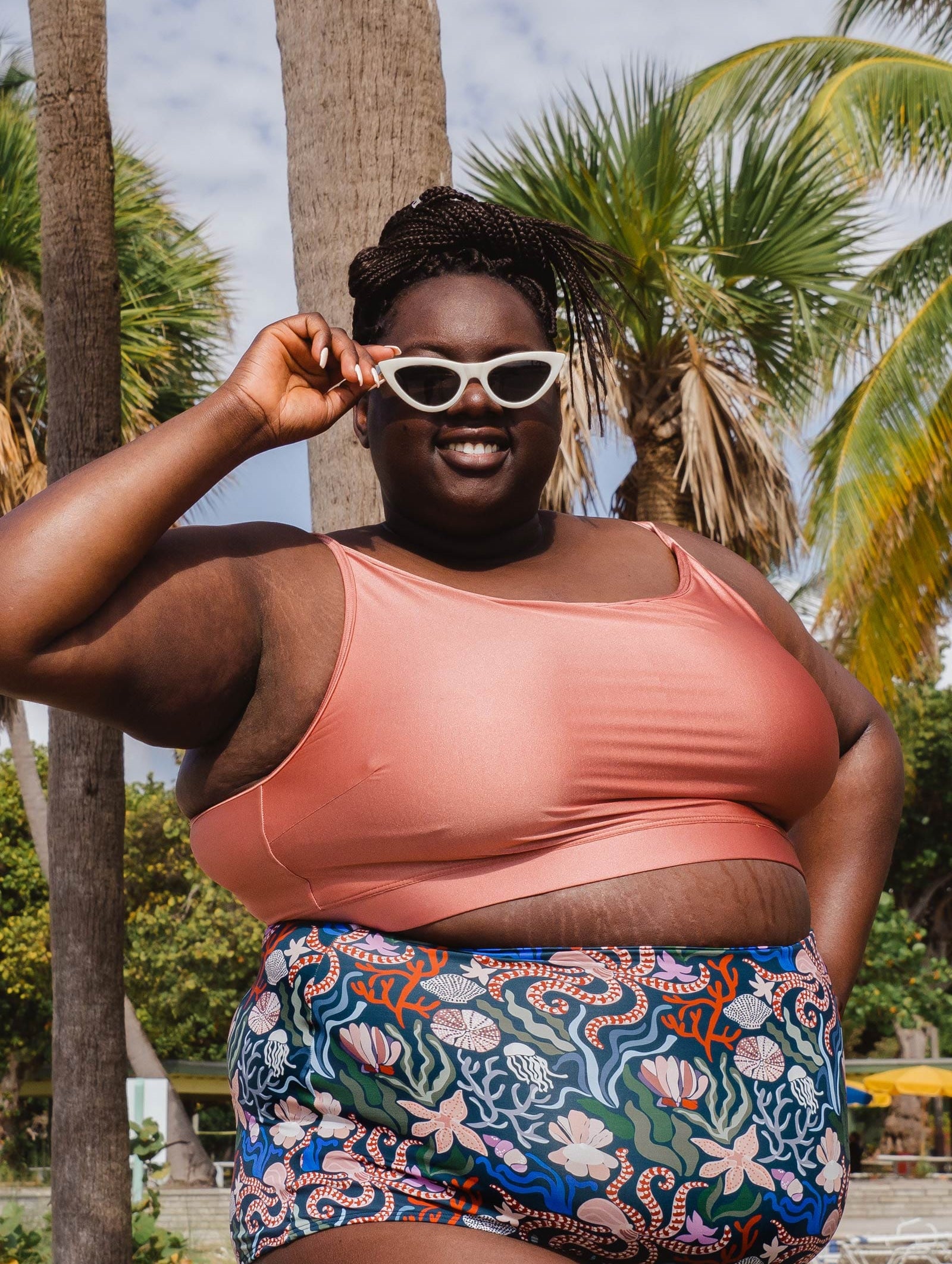 A smiling woman in Miami beach wearing a mimi and august Mango Sunset Bralette Bikini Top and floral bikini bottom