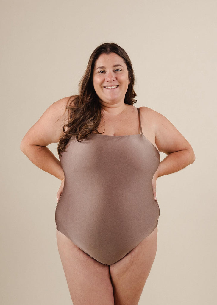 A pregnant woman in a Mimi and August Nohea Dunes One-Piece Swimsuit posing for a picture.