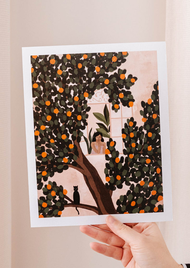 A woman admiring a vibrant Mimi & August Orange Tree Art Print.