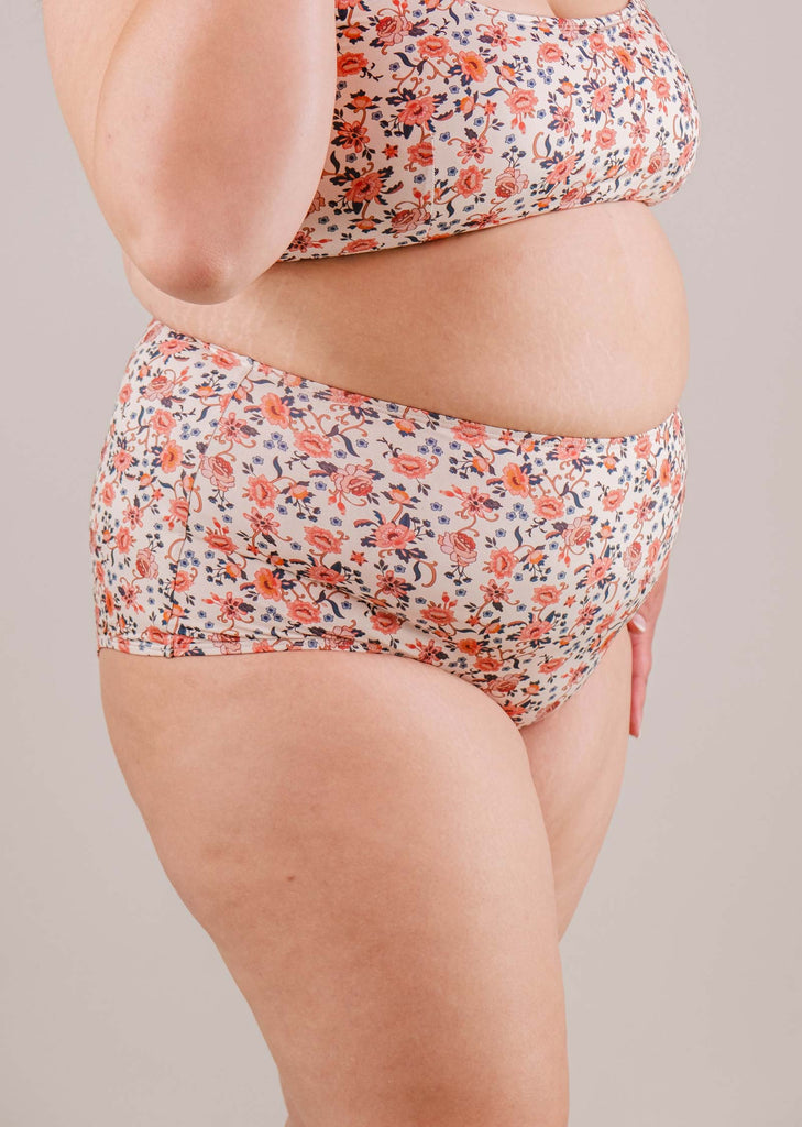 Side view of a plus-size woman wearing a Mimi & August Paloma Amour High Waist Bikini Bottom, focusing on the torso and upper thighs against a neutral backdrop.