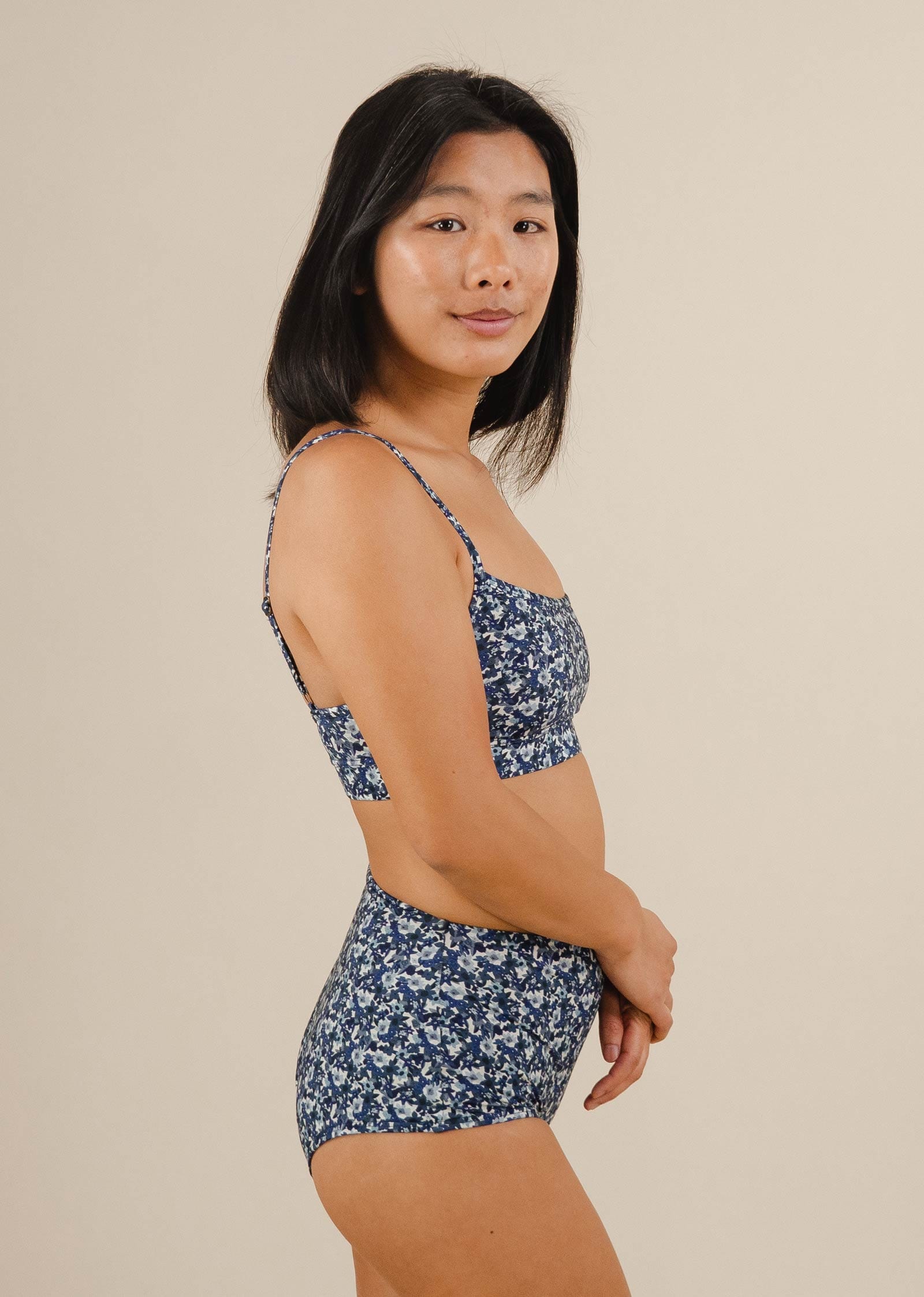 An Asian woman in a Paloma Moonflower High Waist Bikini Bottom posing with floral prints.
