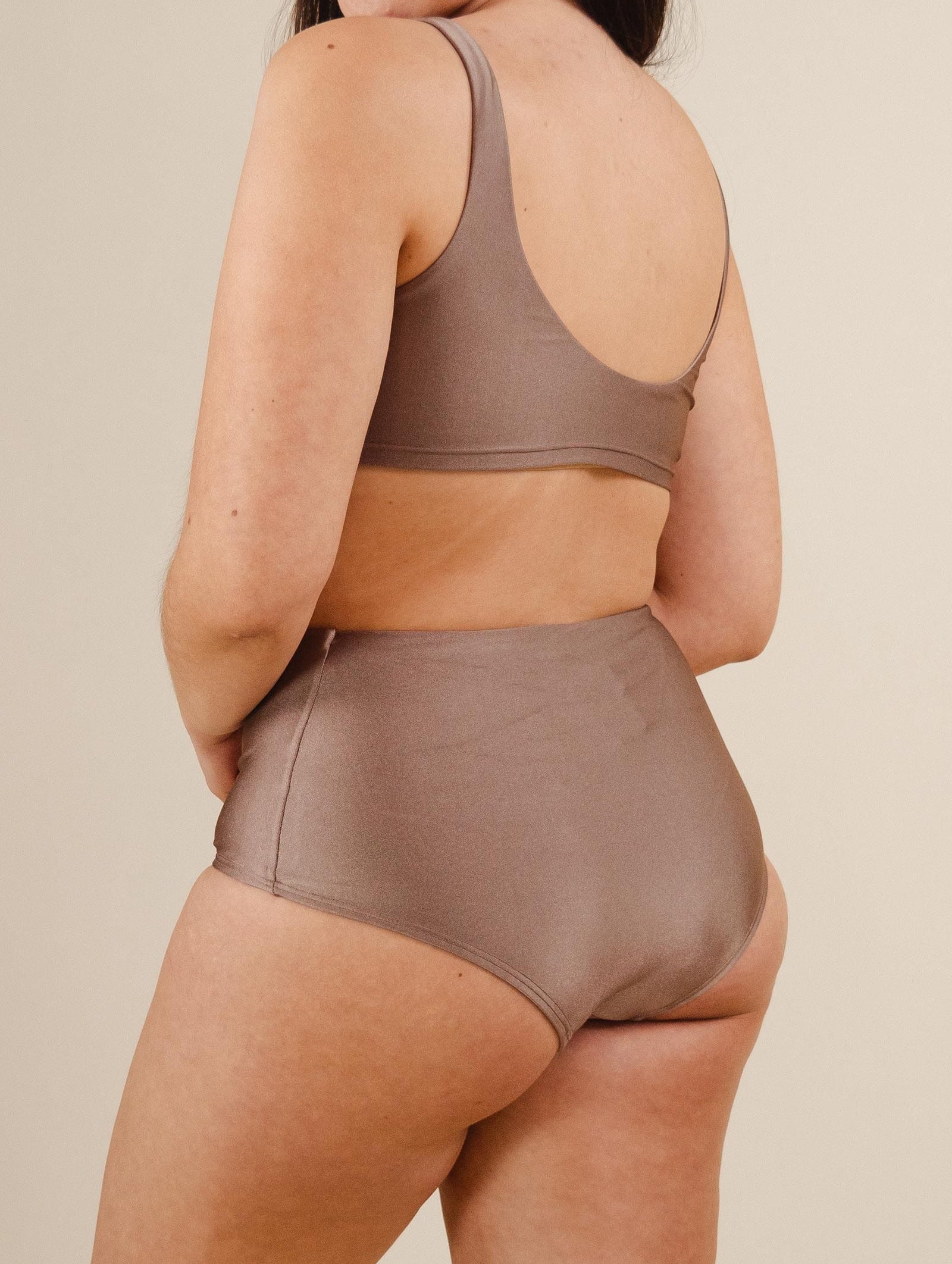 A woman in beige high waist bikini bottoms with very good coverage.