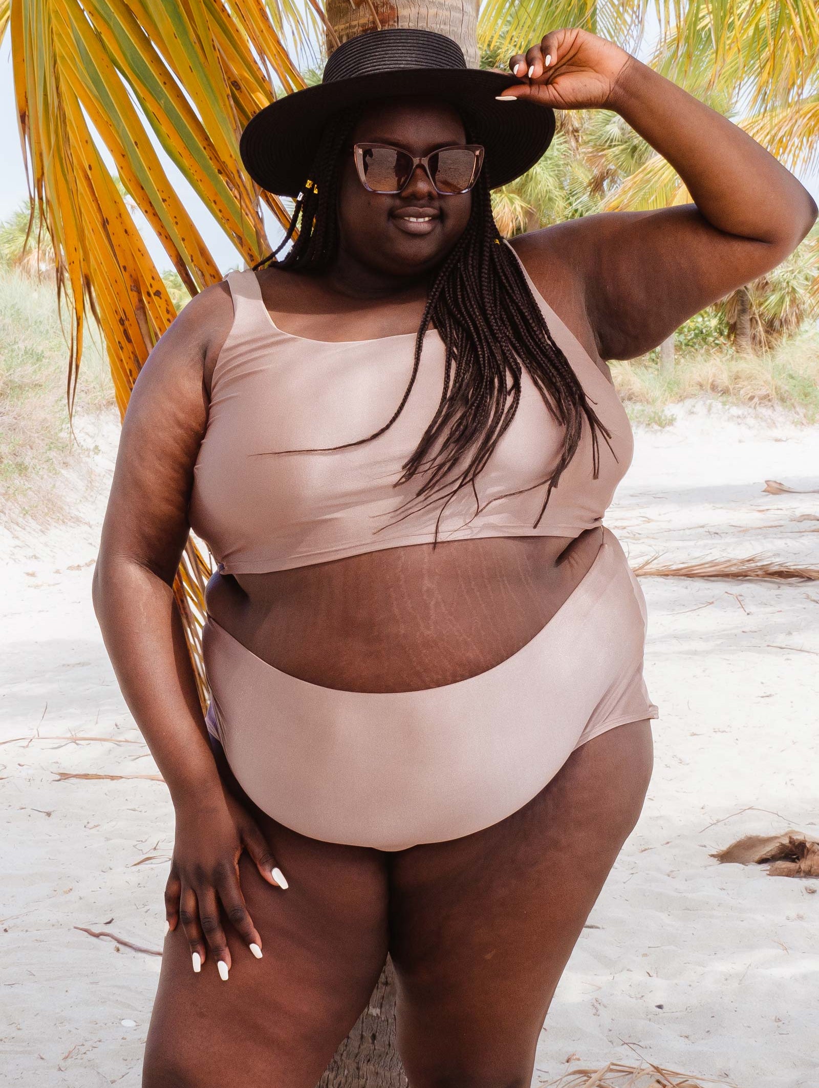 A woman in a Mimi and August Paloma Dunes high waist bikini bottom and hat posing for a picture