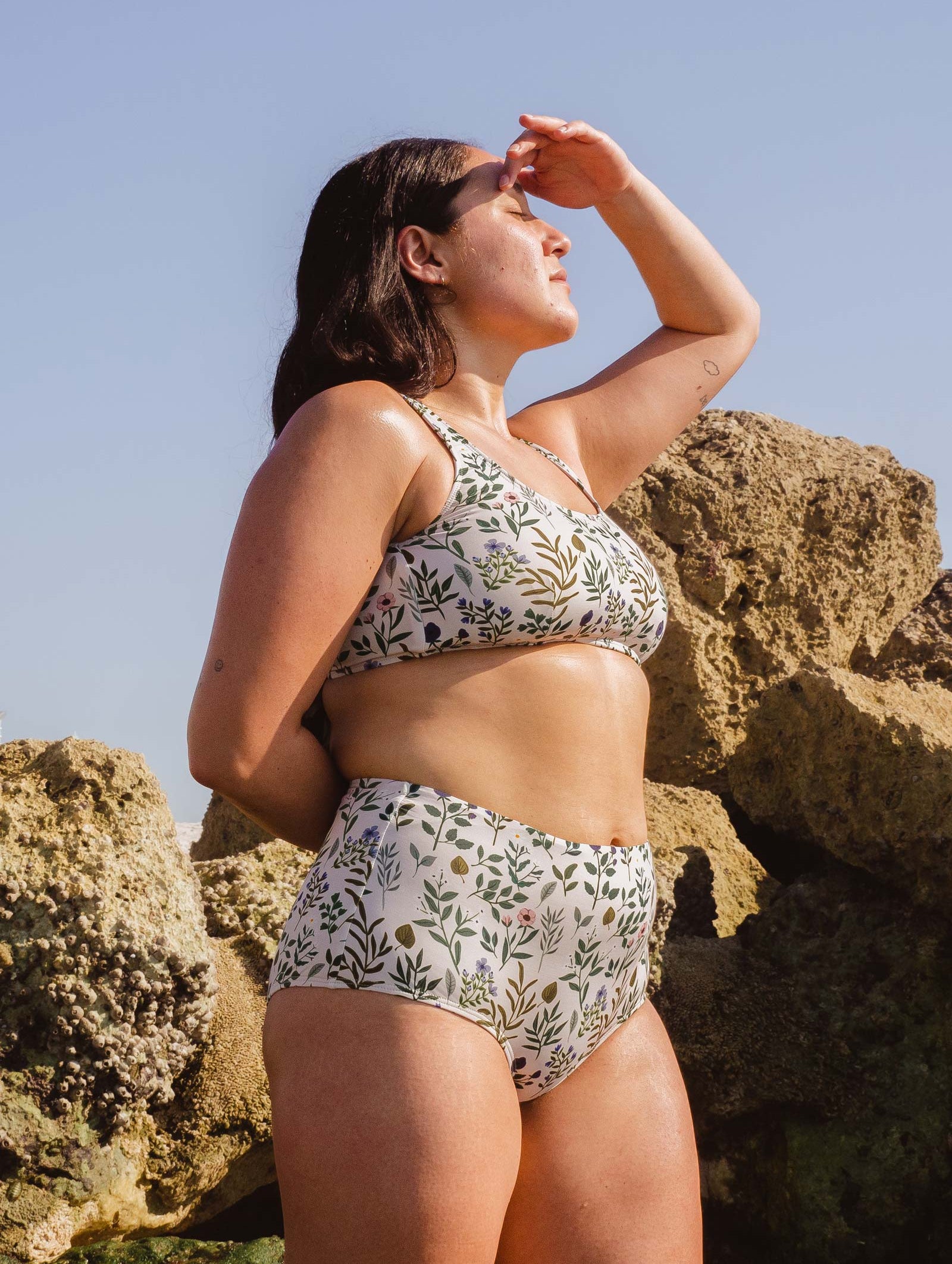 A woman at the beach wearing a Paloma Herboria High Waist Bikini Bottom from mimi and august.