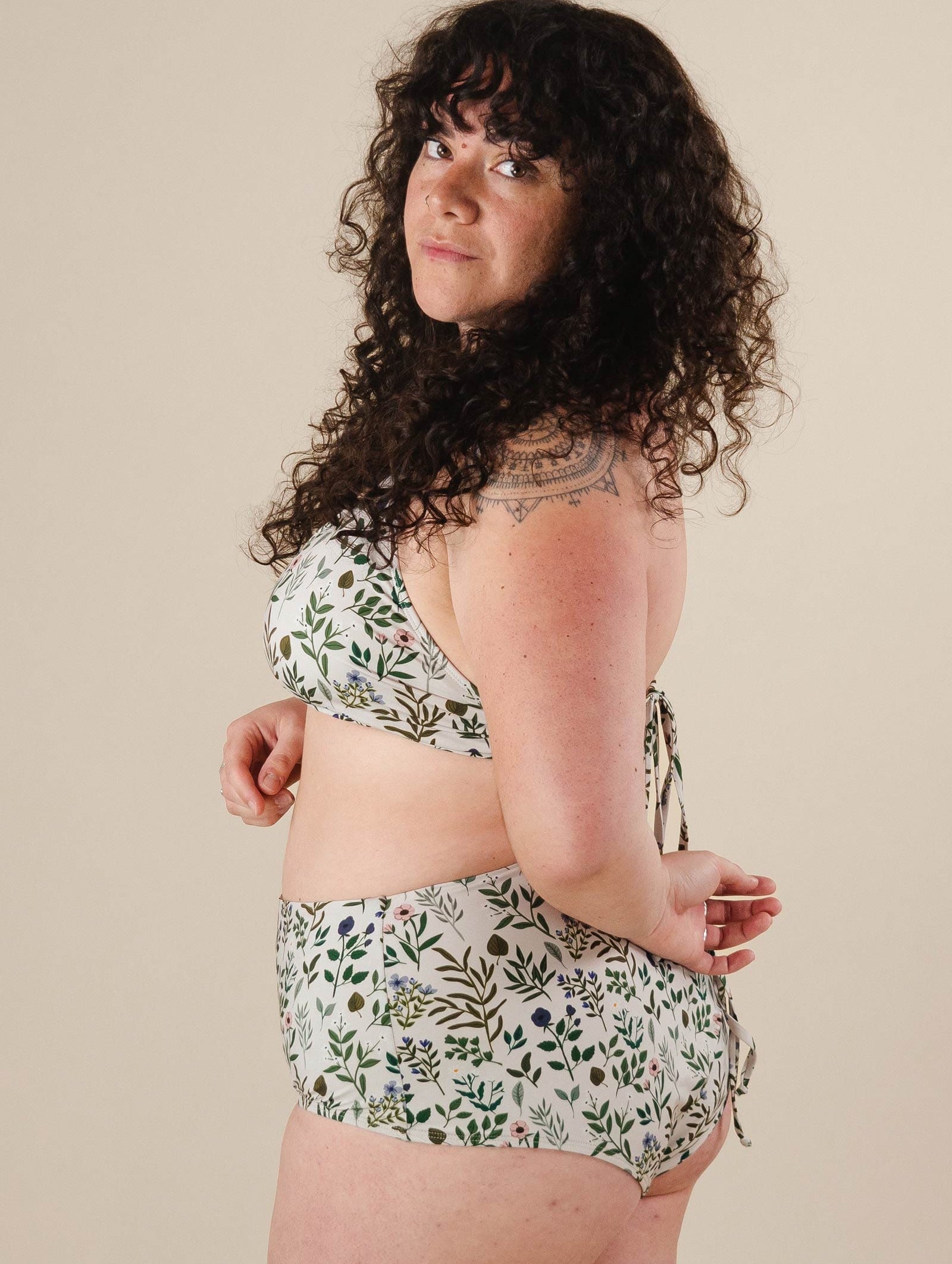 A woman in a Herboria High Waist Bikini Bottom and bikini top posing for a picture.