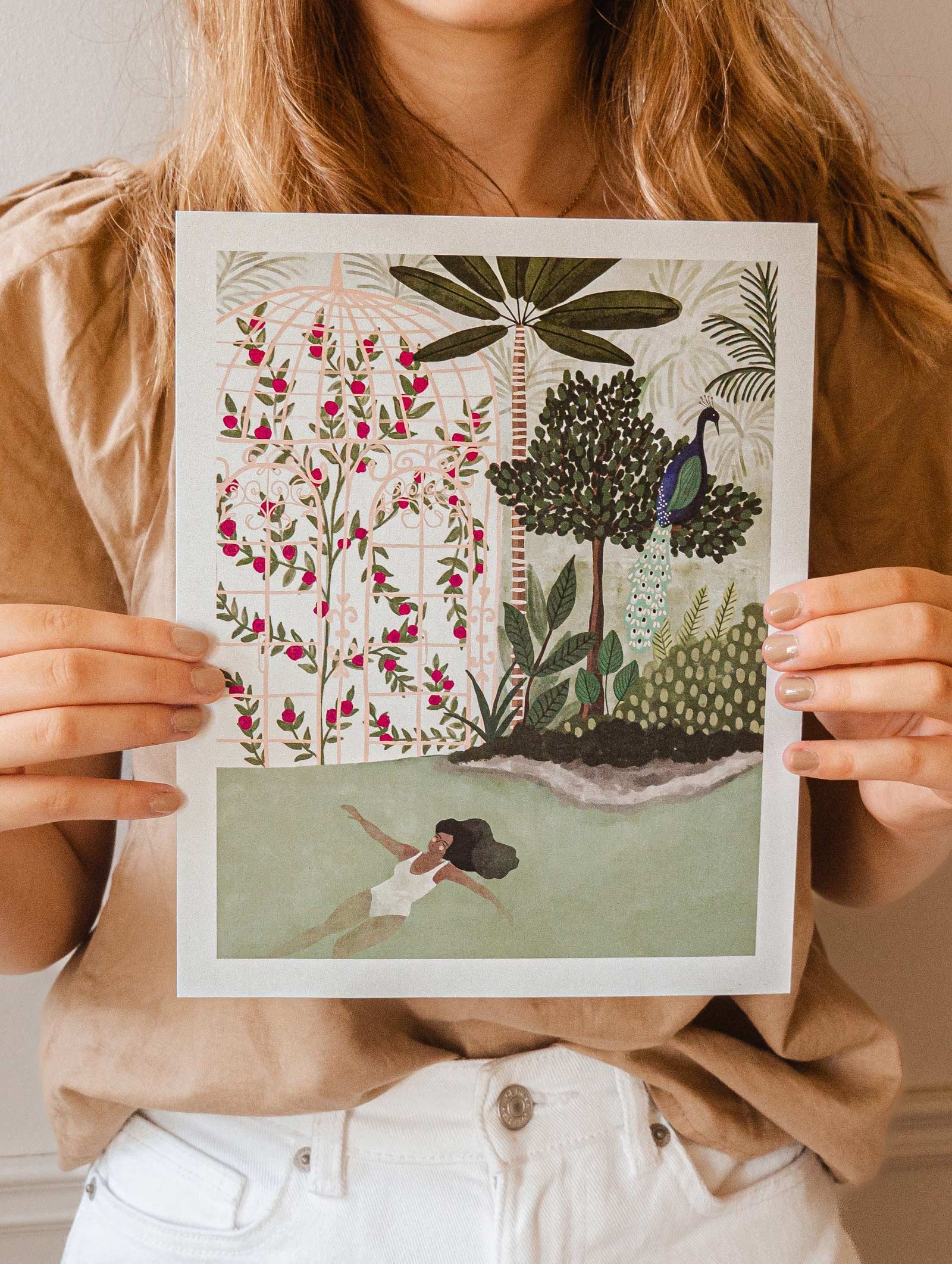 A girl holding up a Peacock Garden Art Print by mimi and august.