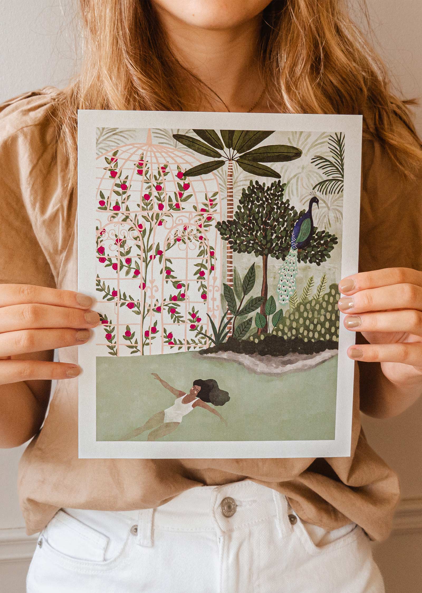 A girl holding up a Peacock Garden Art Print by mimi and august.