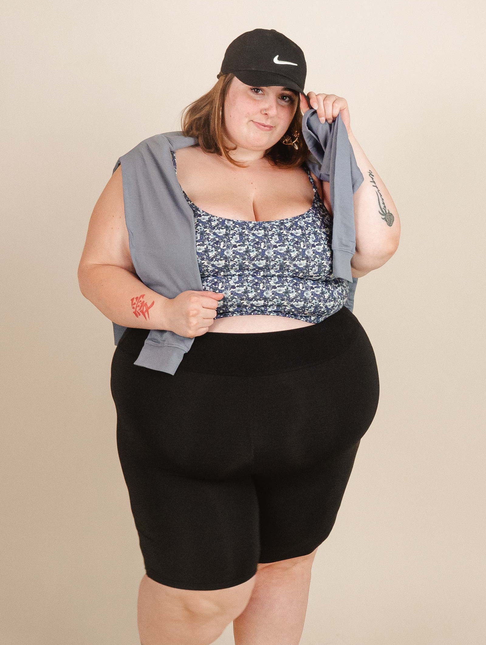 A woman in black shorts by mimi and august with a hat posing for a photo.