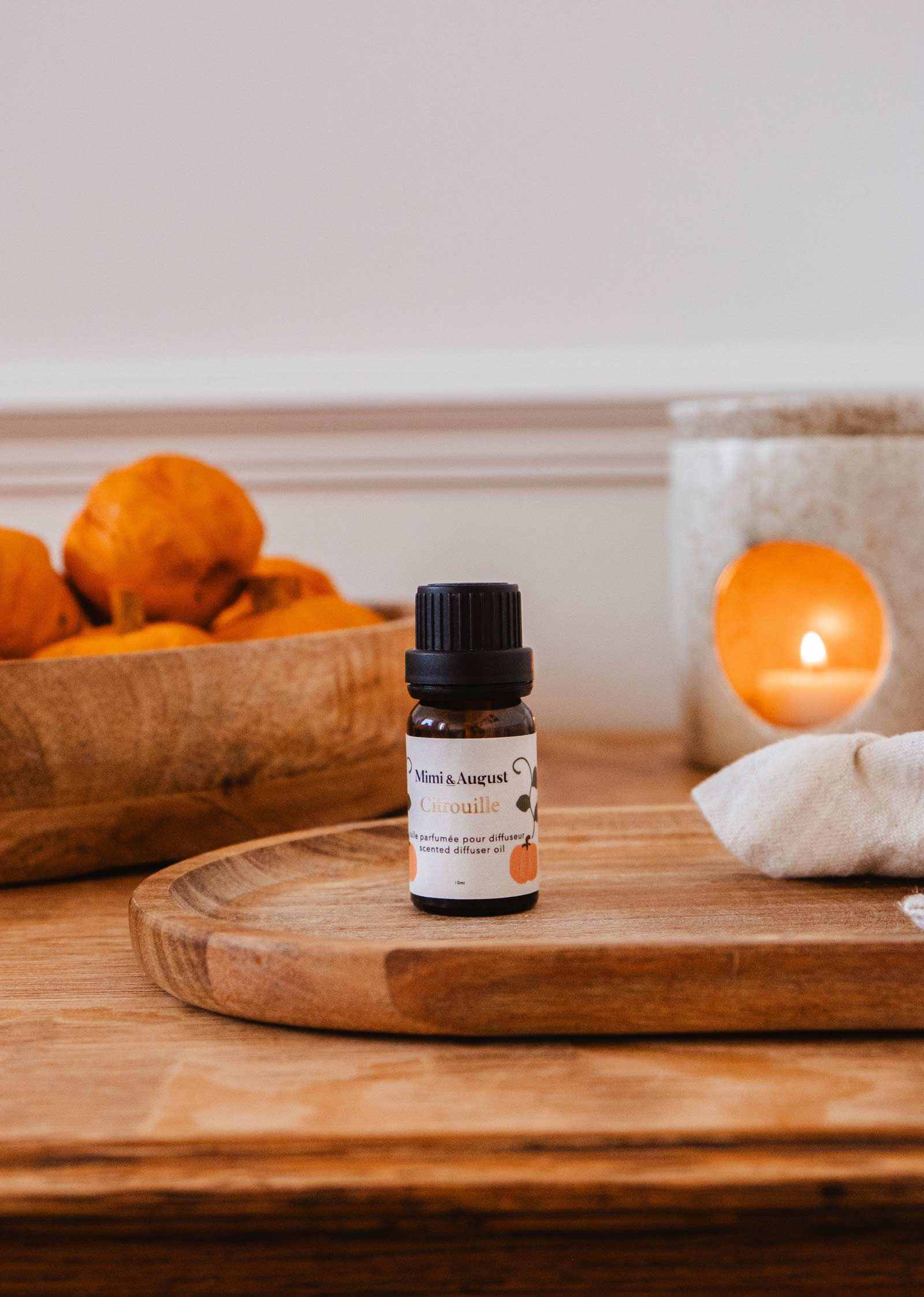 Pumpkin spice scented oil bottle with autumn leaves and warm spices background