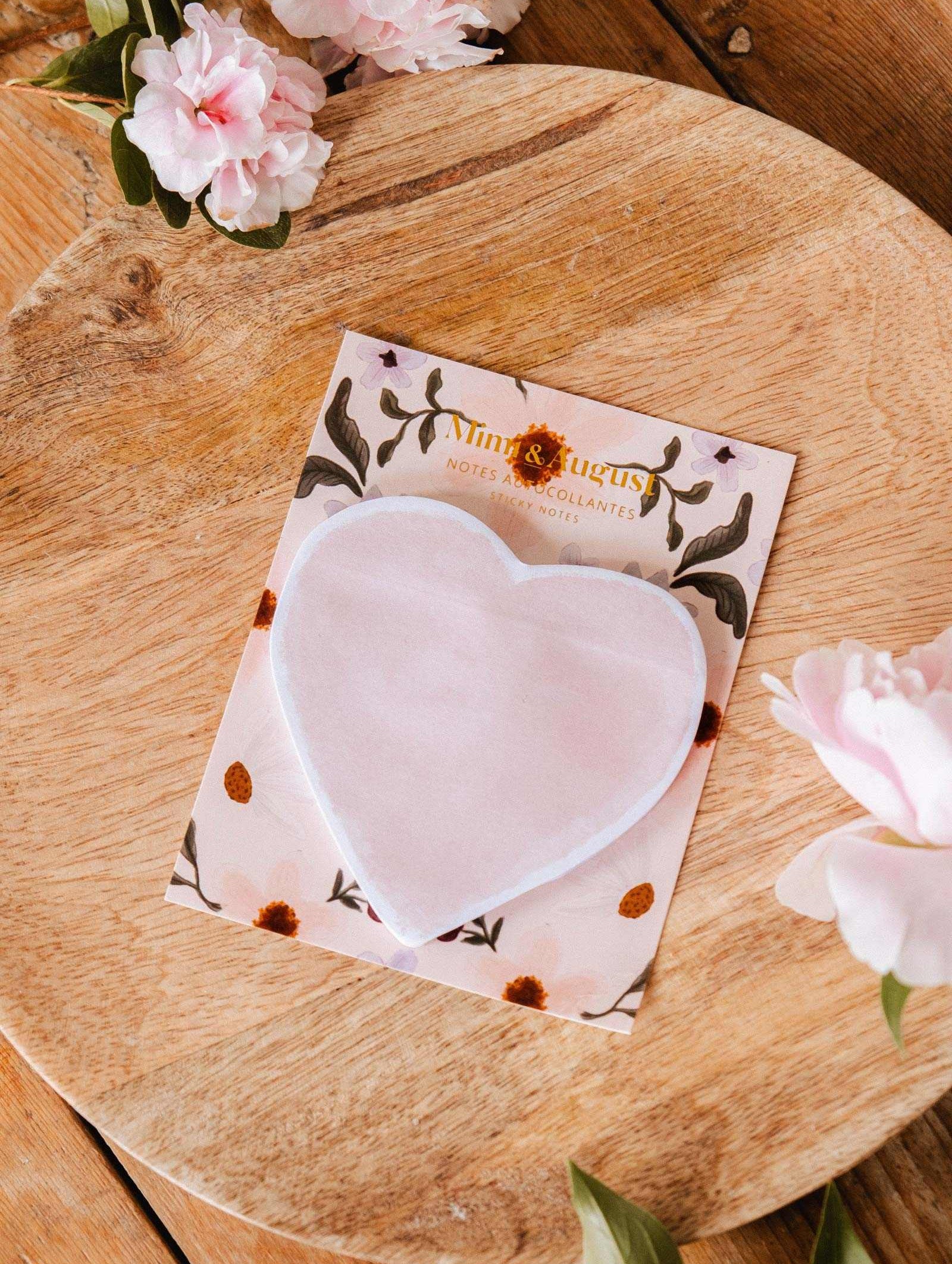 The Soft Heart - Sticky Notes by Mimi & August rest on a floral backing card atop a round wooden board, with pink flowers nearby.