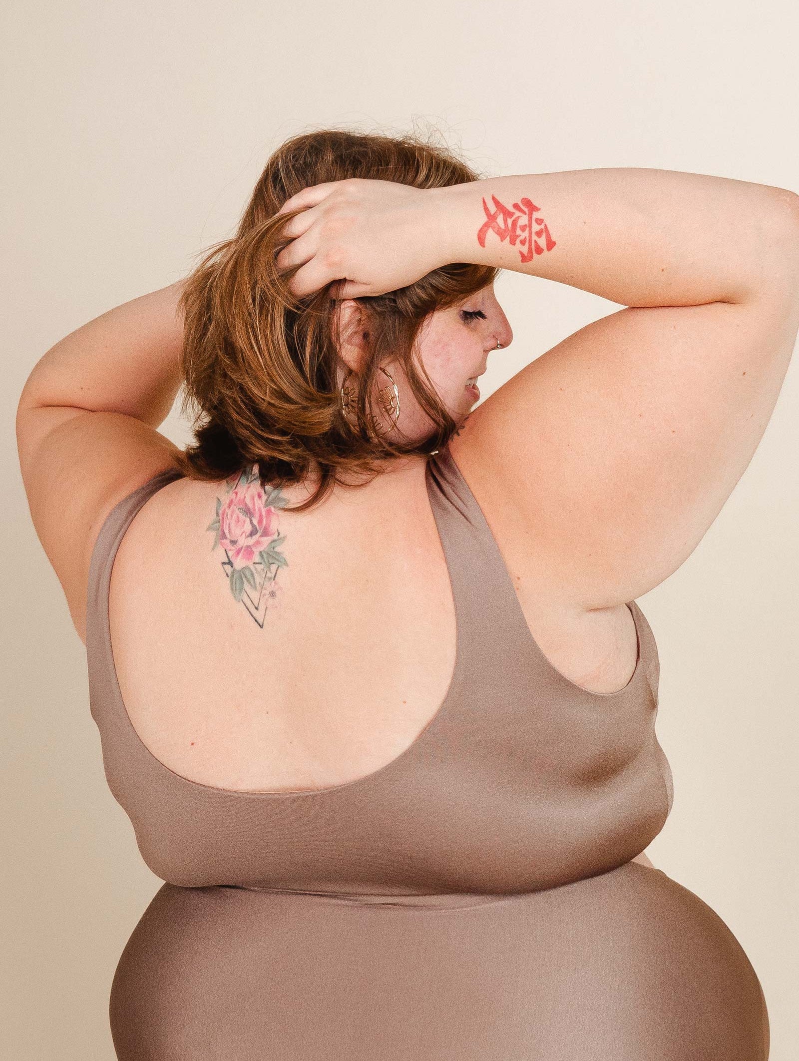 a woman in a brown Tahiti Bikini Top from mimi and august, with a floral print tattoo on her back.