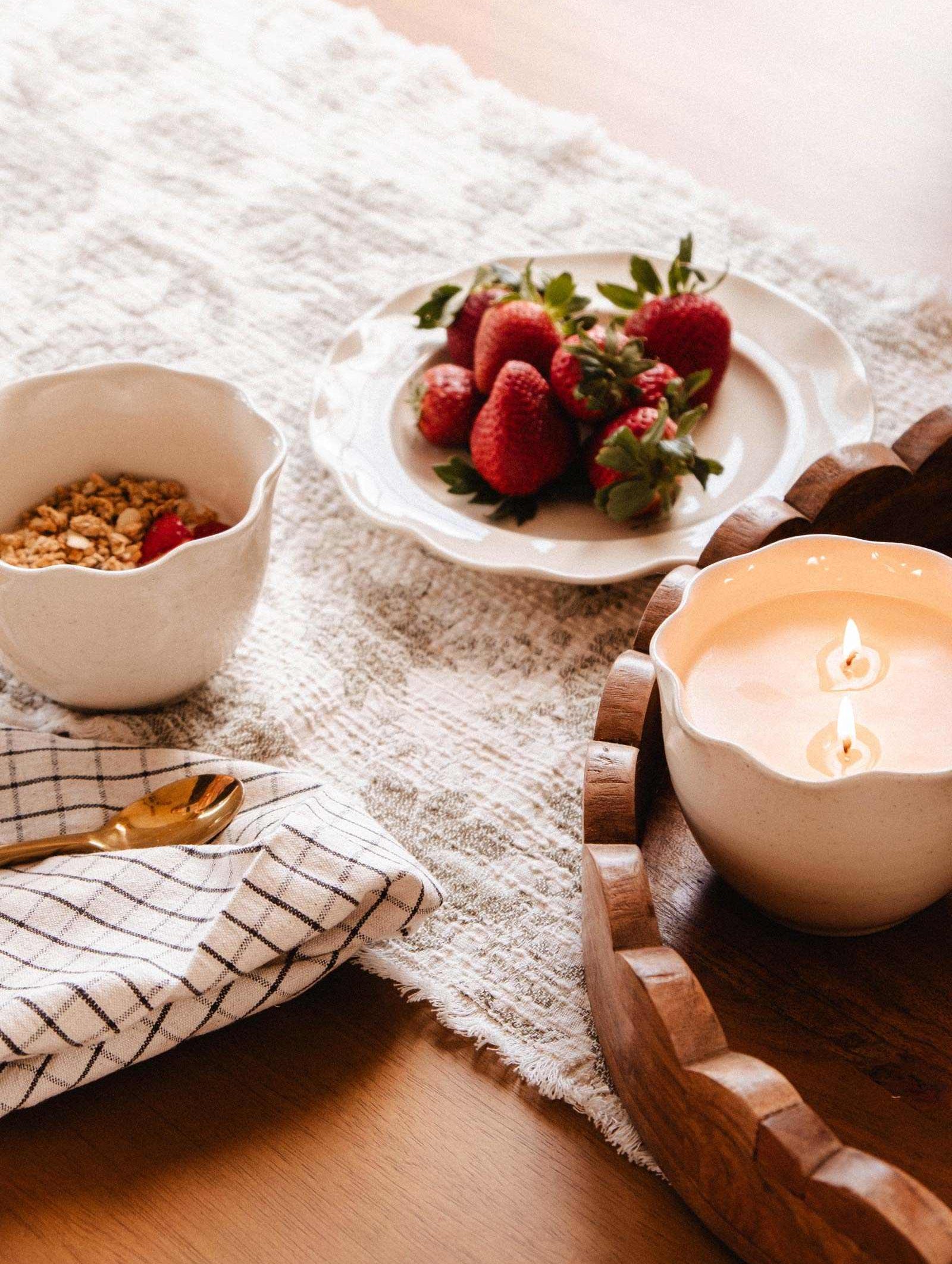 The Petal Bowl Candle by Mimi & August, artfully arranged with granola, fresh strawberries, and a gold spoon on a checkered cloth, makes a thoughtful Mother's Day gift.