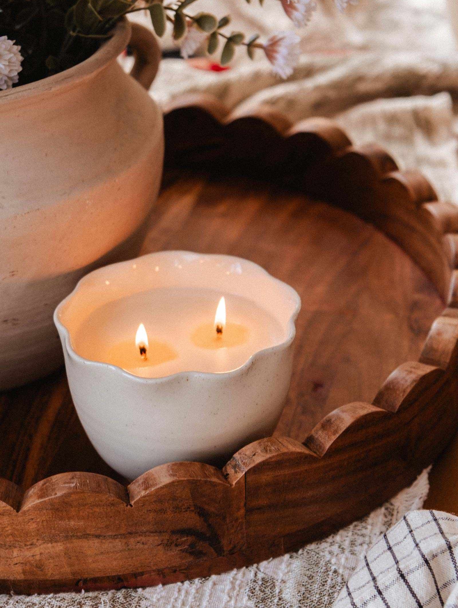 The Petal Bowl Candle by Mimi & August features a handcrafted ceramic bowl with two flames, presented on a wooden tray beside a vase—an elegant gift for Mother’s Day.