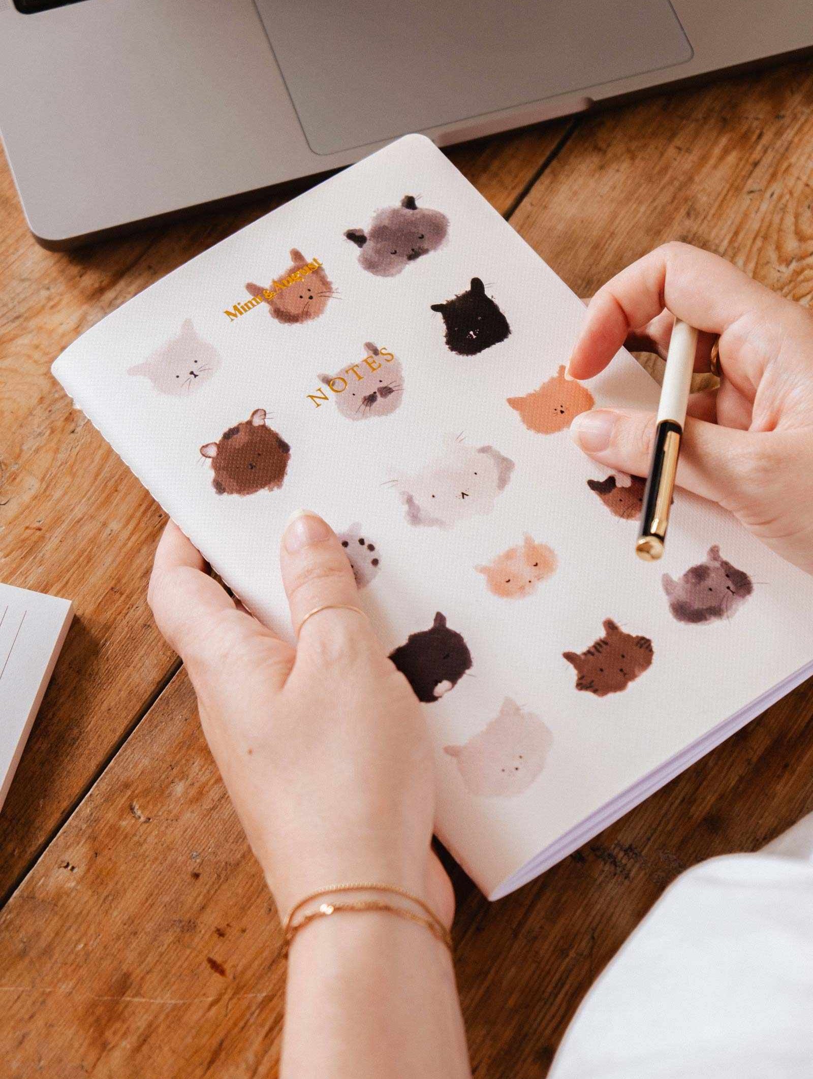 Softcover purr-fect cat notebook with 100 lined pages and playful kitty faces cover