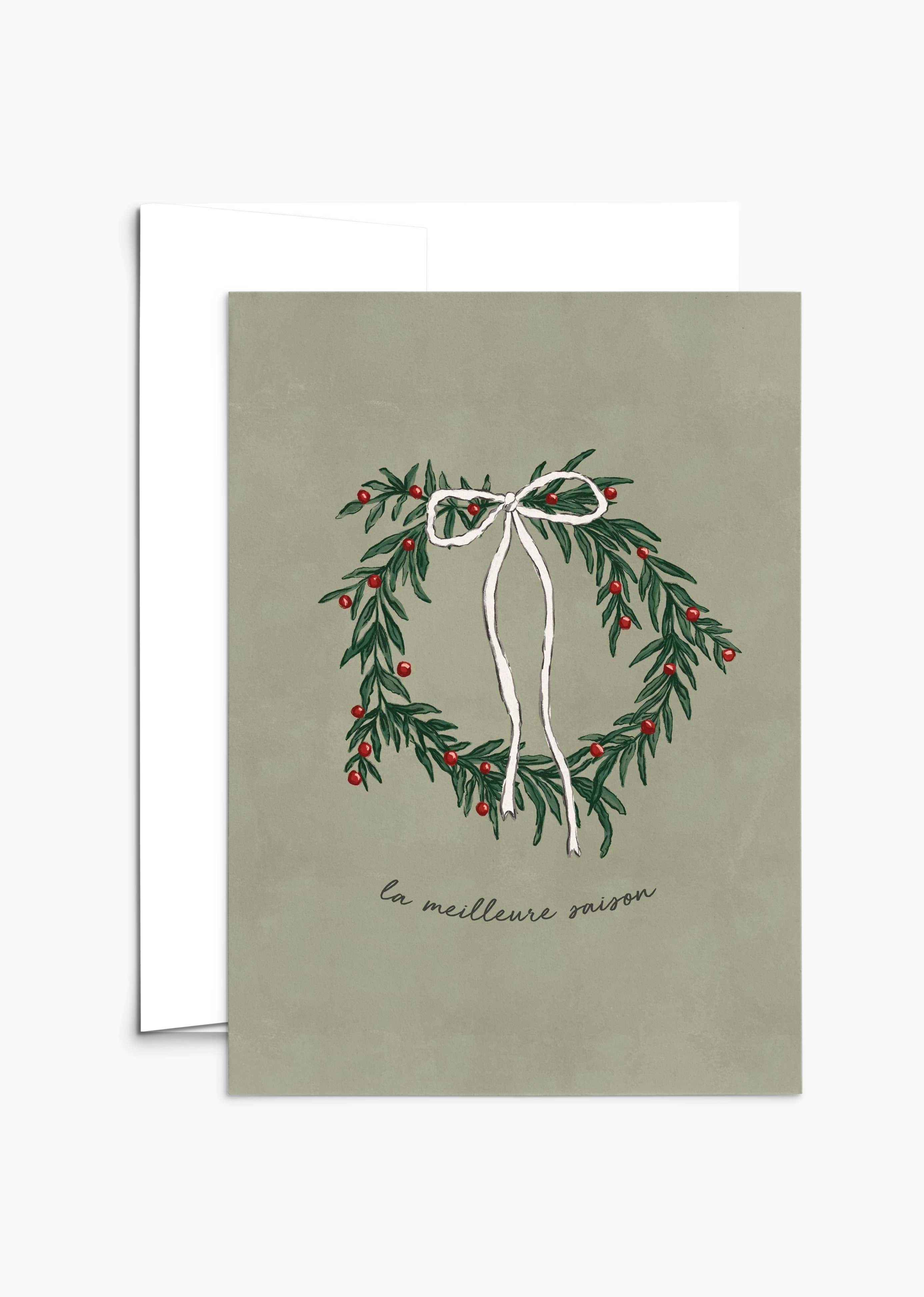 The Best Season Christmas Greeting Card by Mimi & August features an illustrated wreath with red berries and a white ribbon on green, "la meilleure saison" text, is blank inside, and printed on recycled paper.
