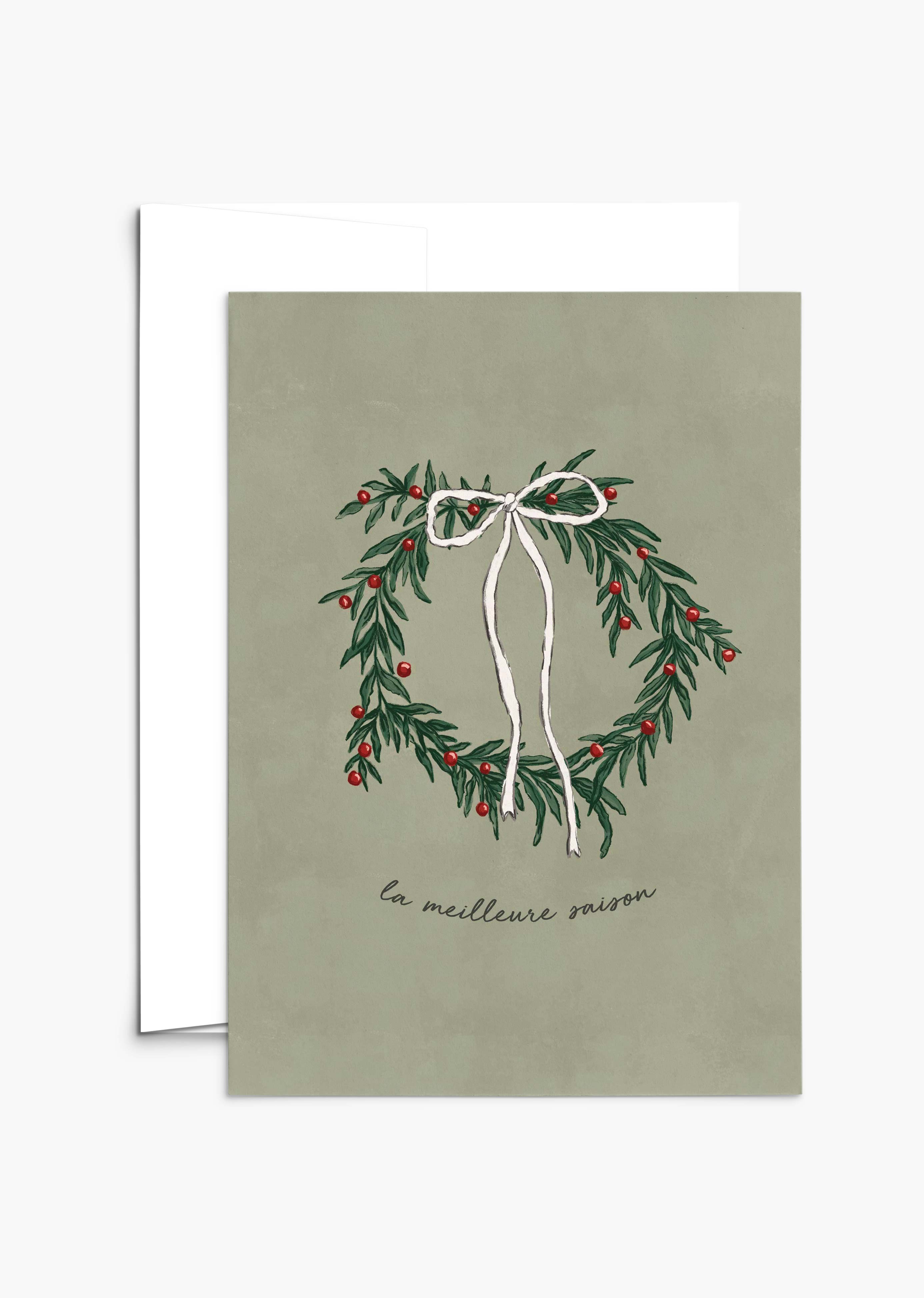 The Best Season Christmas Greeting Card by Mimi & August features an illustrated wreath with red berries and a white ribbon on green, "la meilleure saison" text, is blank inside, and printed on recycled paper.