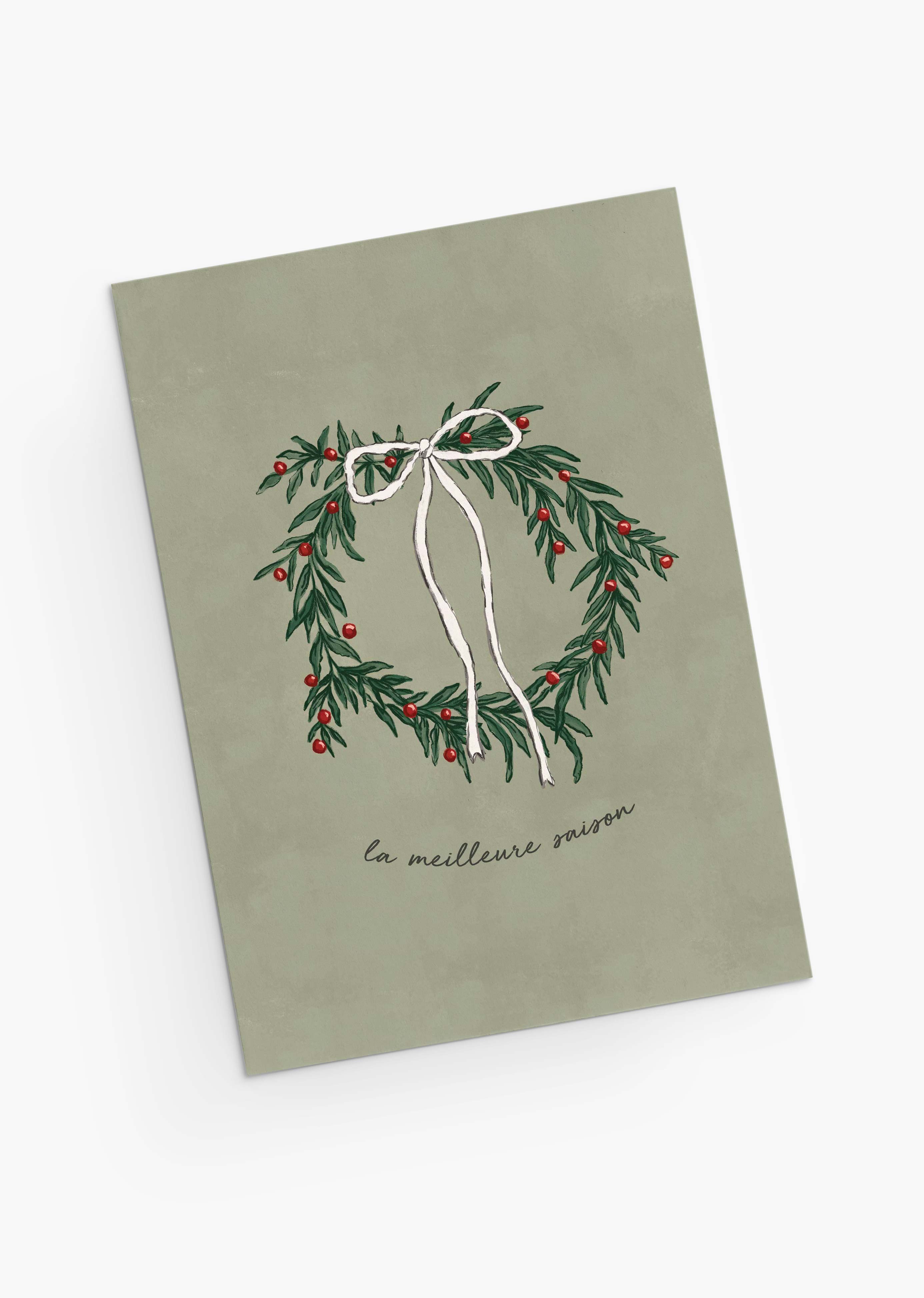 The Best Season Christmas Greeting Card by Mimi & August features an illustrated wreath with a white bow and red berries, “la meilleure saison” text on muted green, is blank inside for your message, and printed on recycled paper.