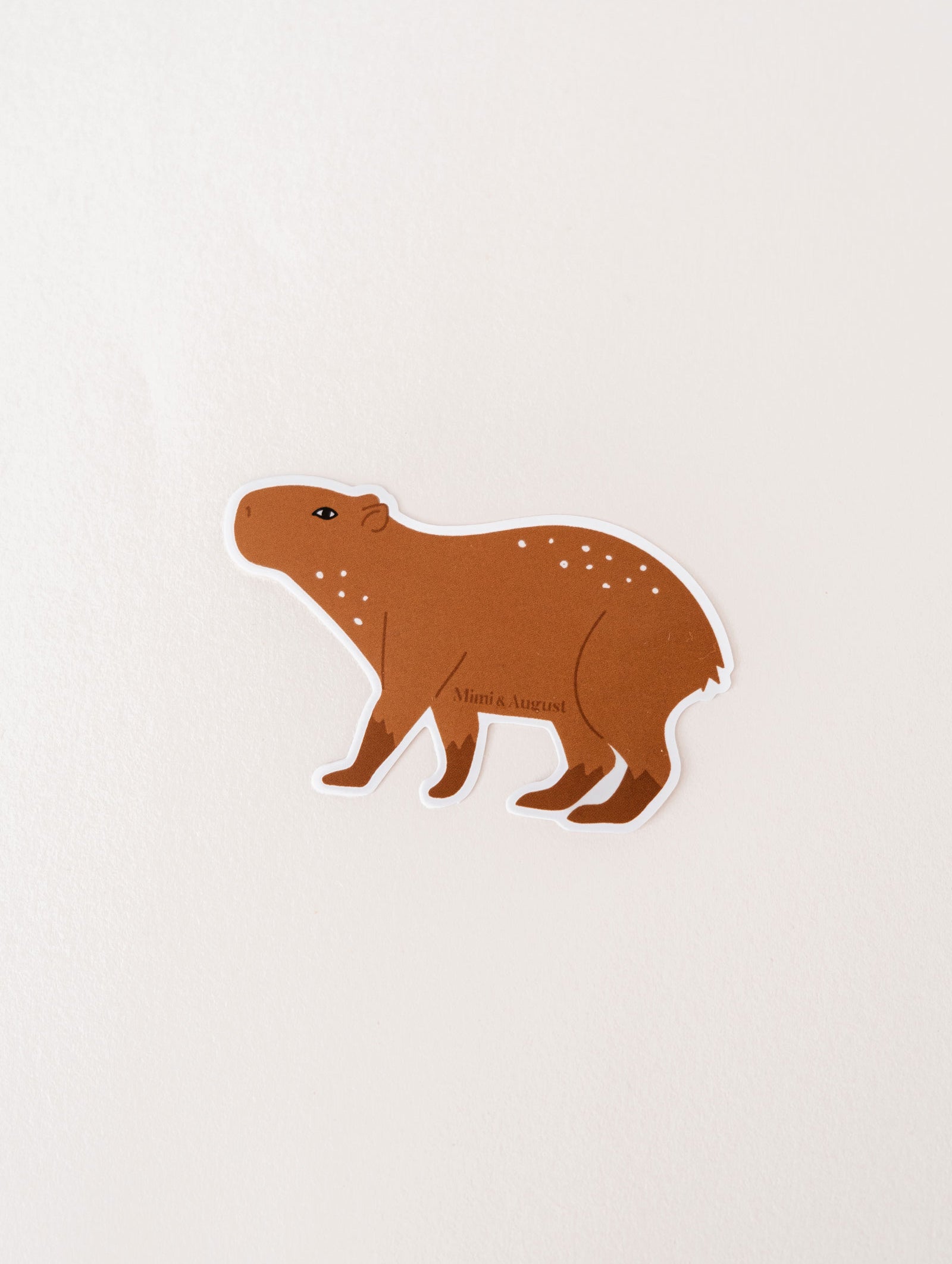 A waterproof Mimi & August vinyl sticker featuring a Capybara on a white surface.